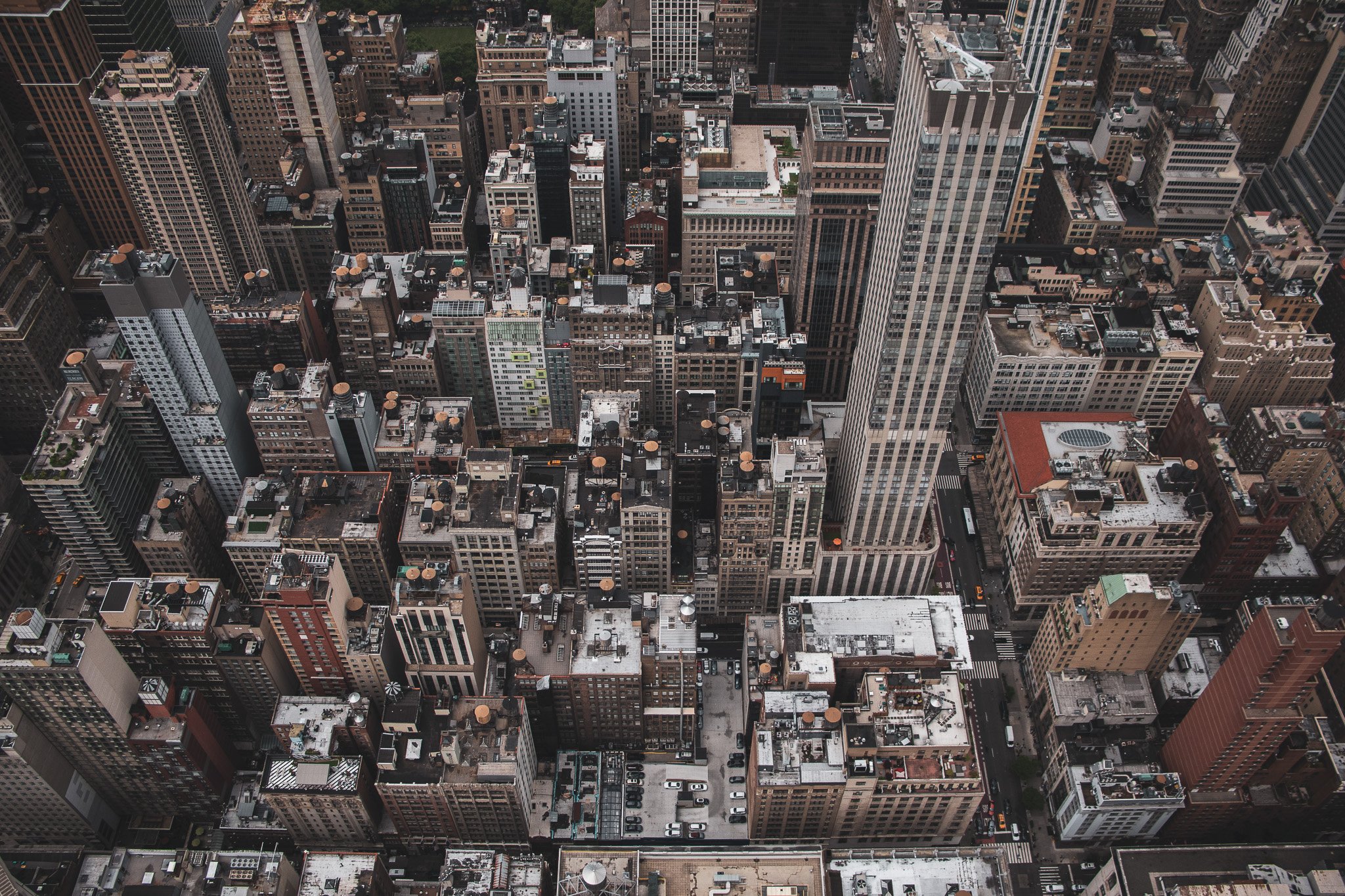 Aerial view of densely packed skyscrapers in a city, with rooftops, HVAC units, and various structures visible on top of the buildings.