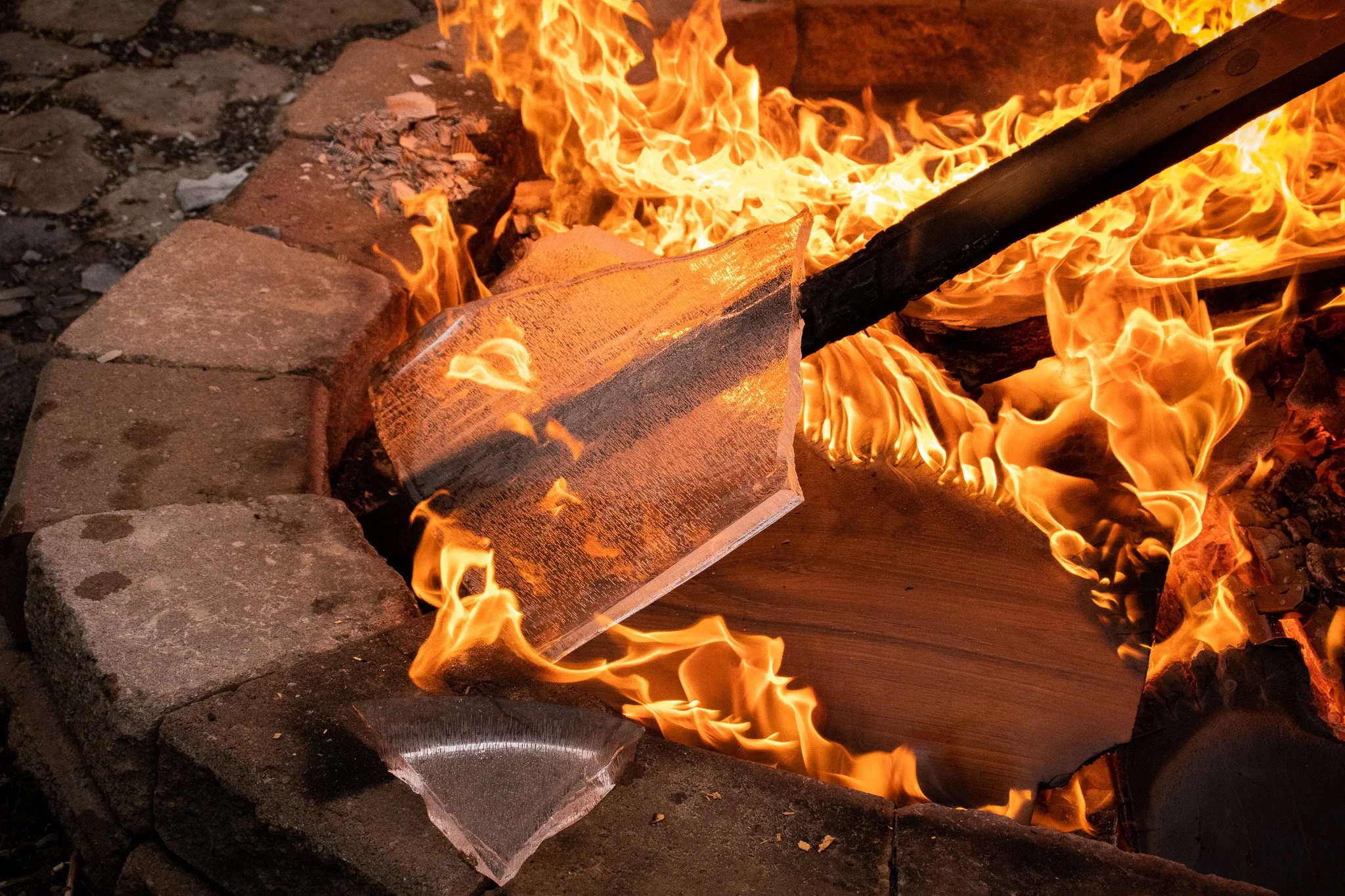 A fire burning wood and stone in an outdoor stone fireplace