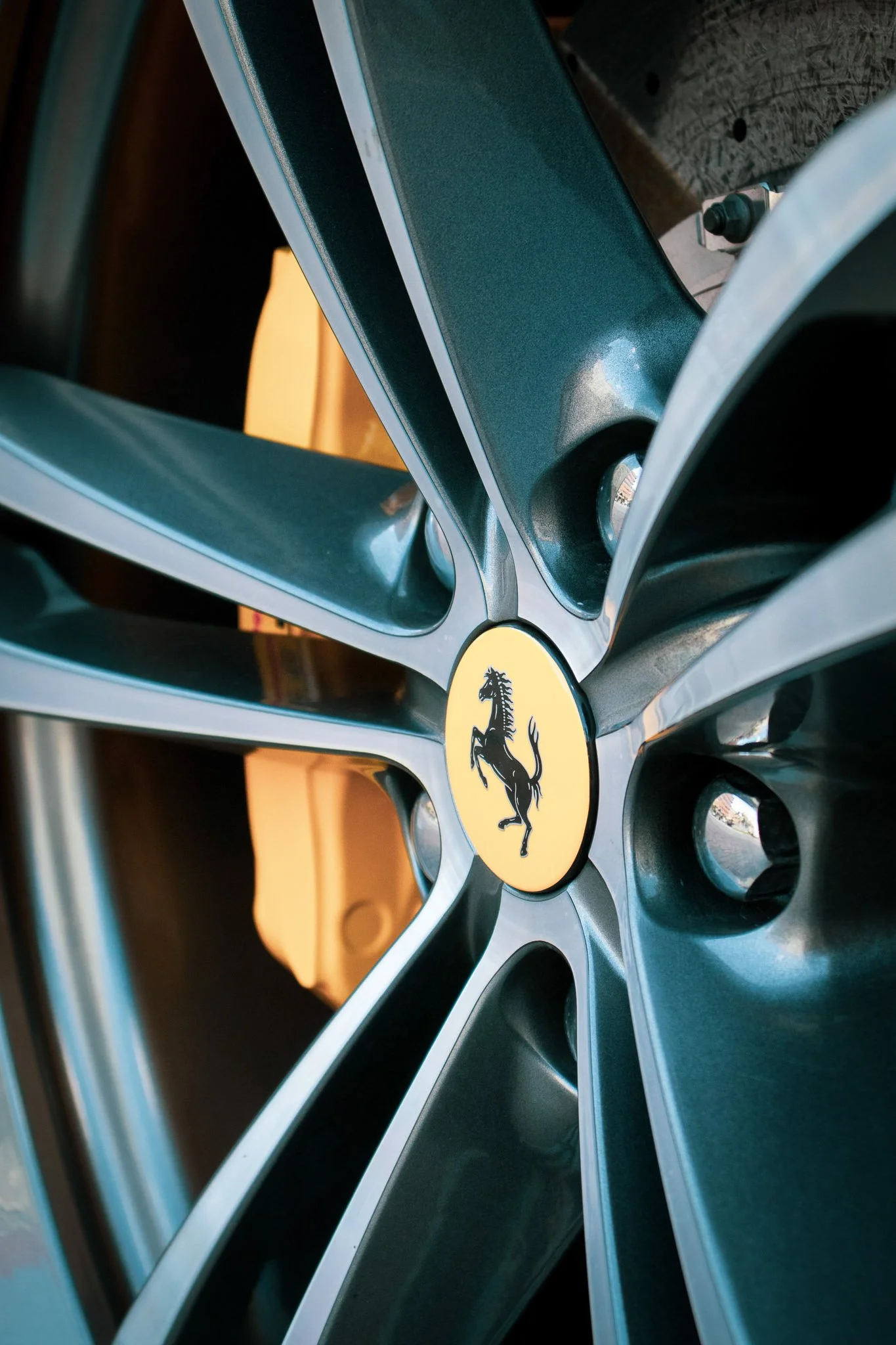 Close-up of a Ferrari wheel with a yellow Ferrari logo at the center, showing black and silver alloy spokes.