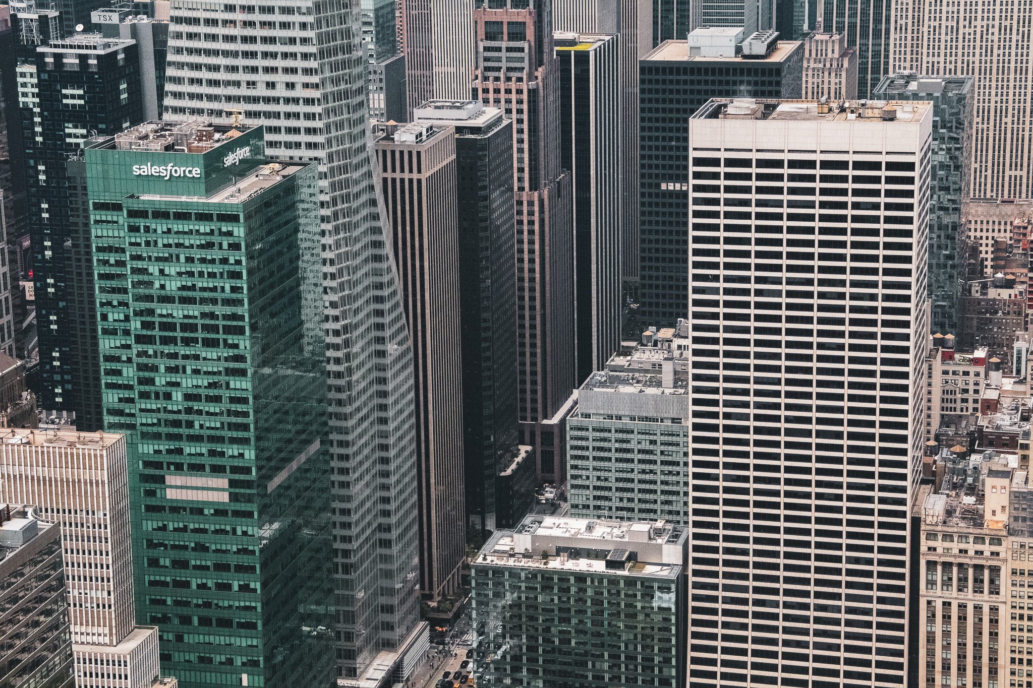 Aerial view of a dense cityscape with numerous high-rise office buildings, including one with the Salesforce logo on the top, in a downtown urban area.