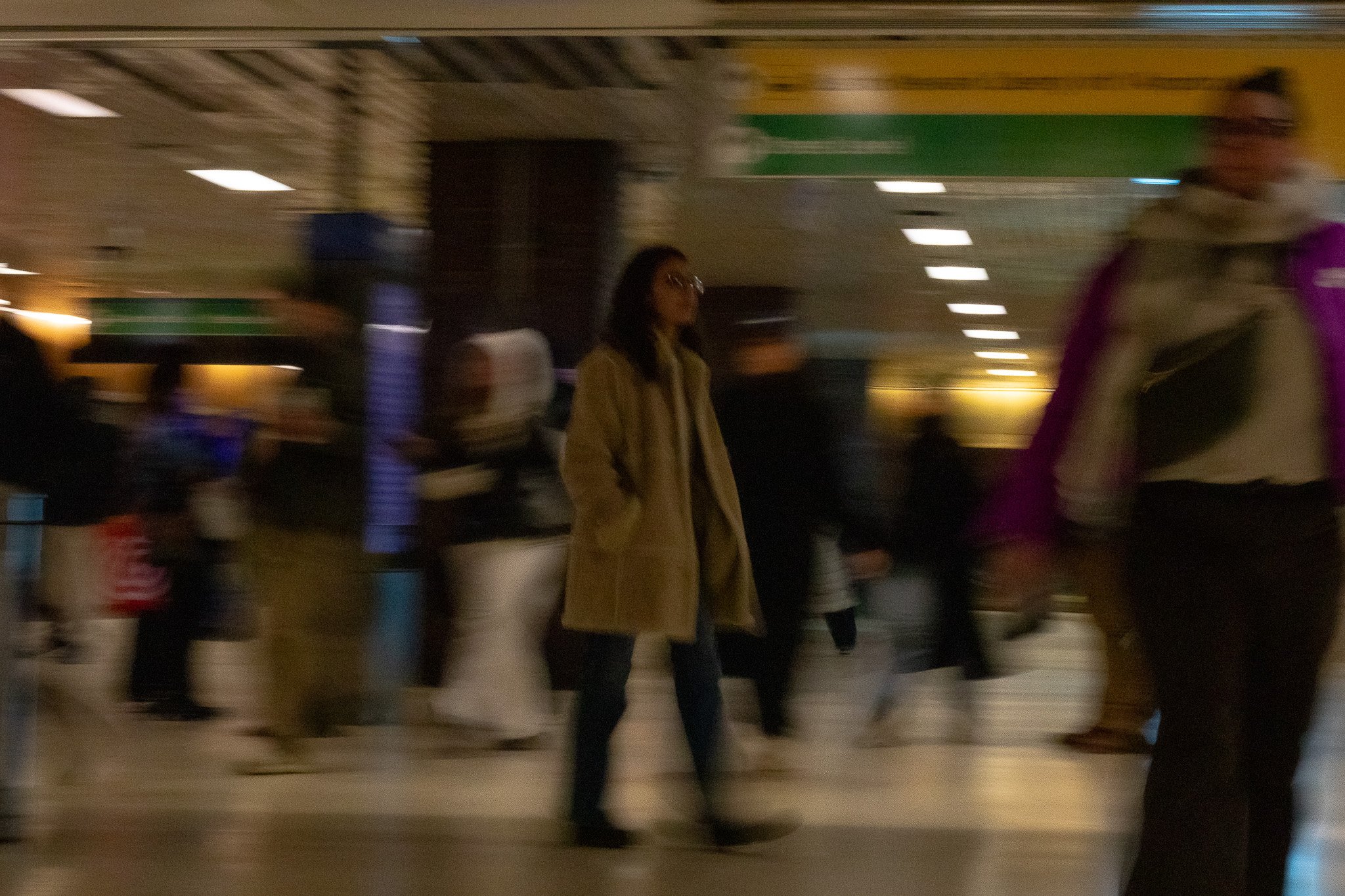 Blurred image of people walking in an indoor public space, possibly a mall or airport.