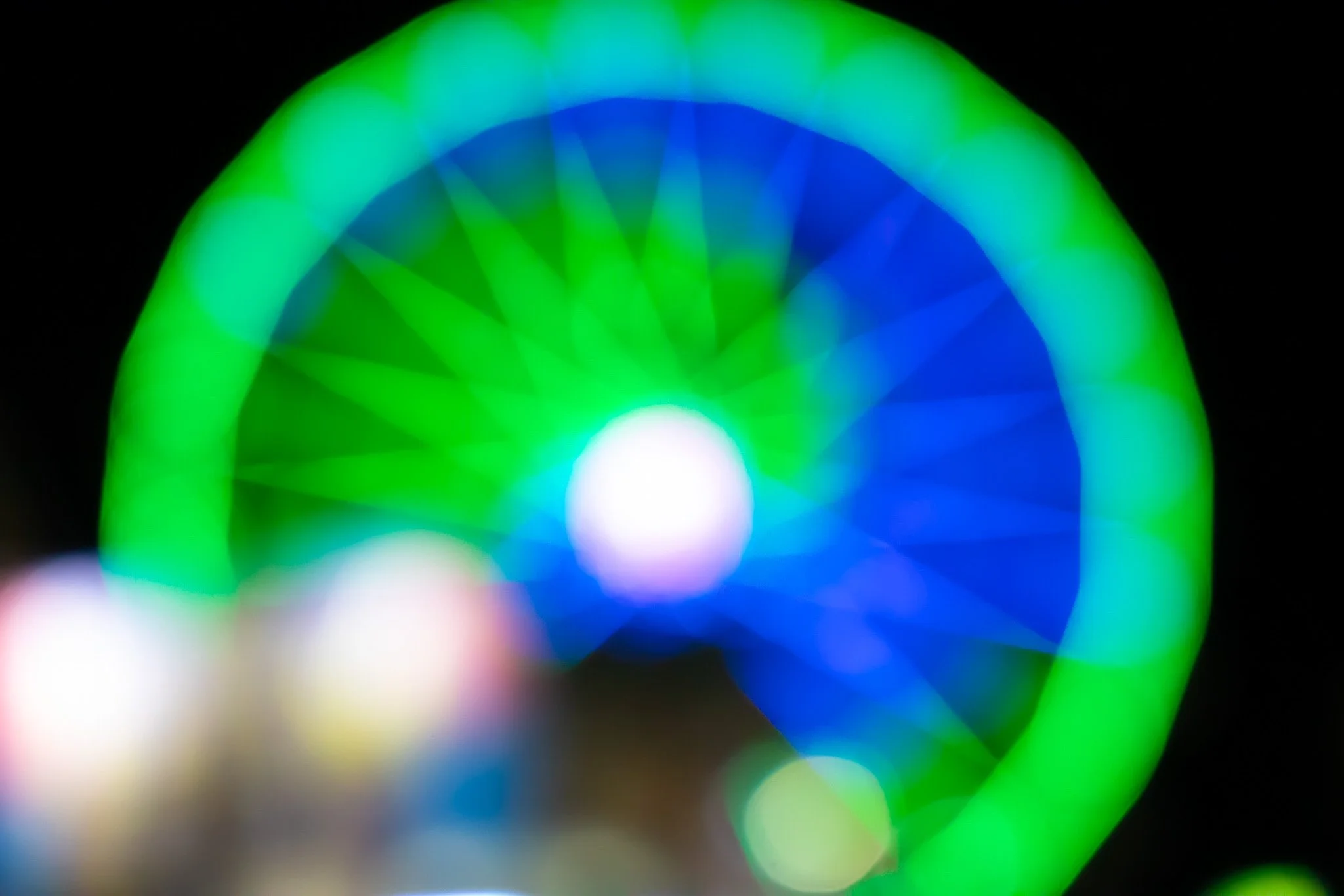 Abstract image with vibrant green, blue, and white light streaks and bokeh effects against a black background.