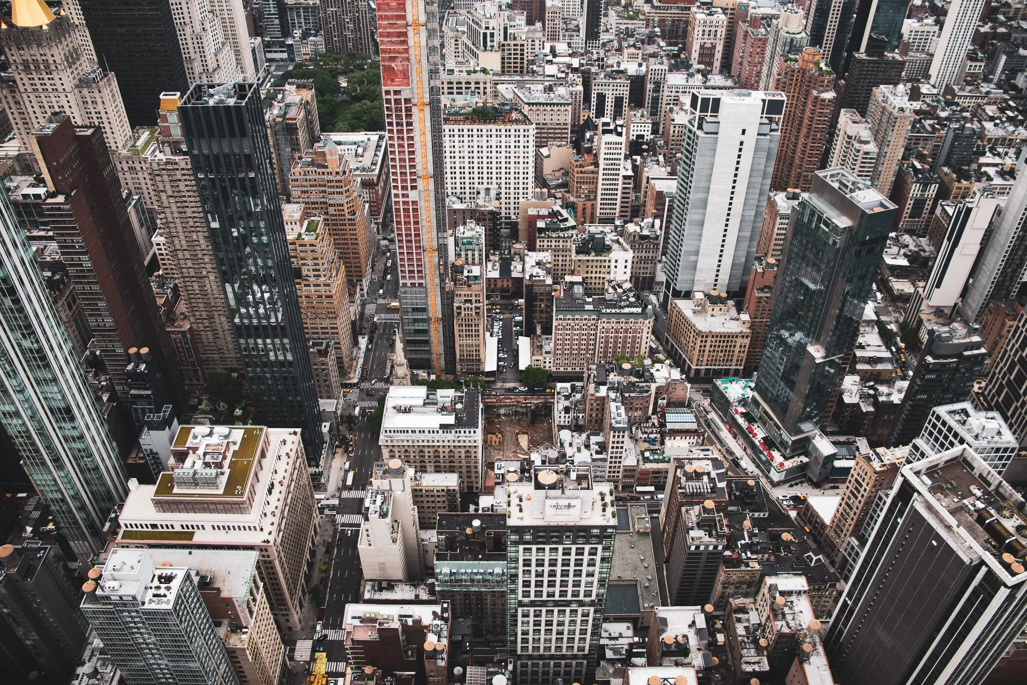 An aerial view of a dense cityscape with numerous tall skyscrapers, buildings, and streets in a metropolitan downtown area.