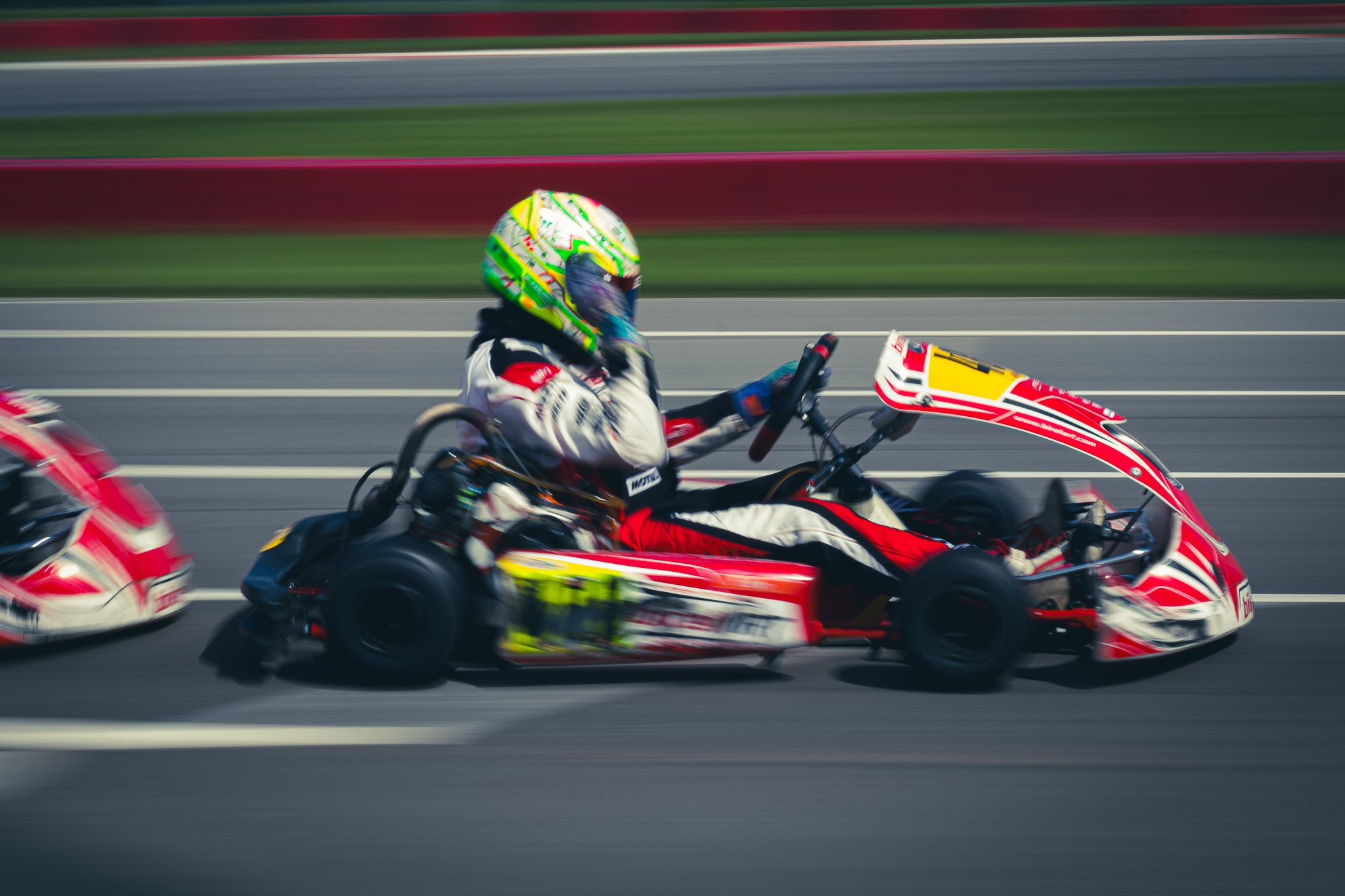 Motorsport race car drifting on the track with a driver wearing a colorful helmet