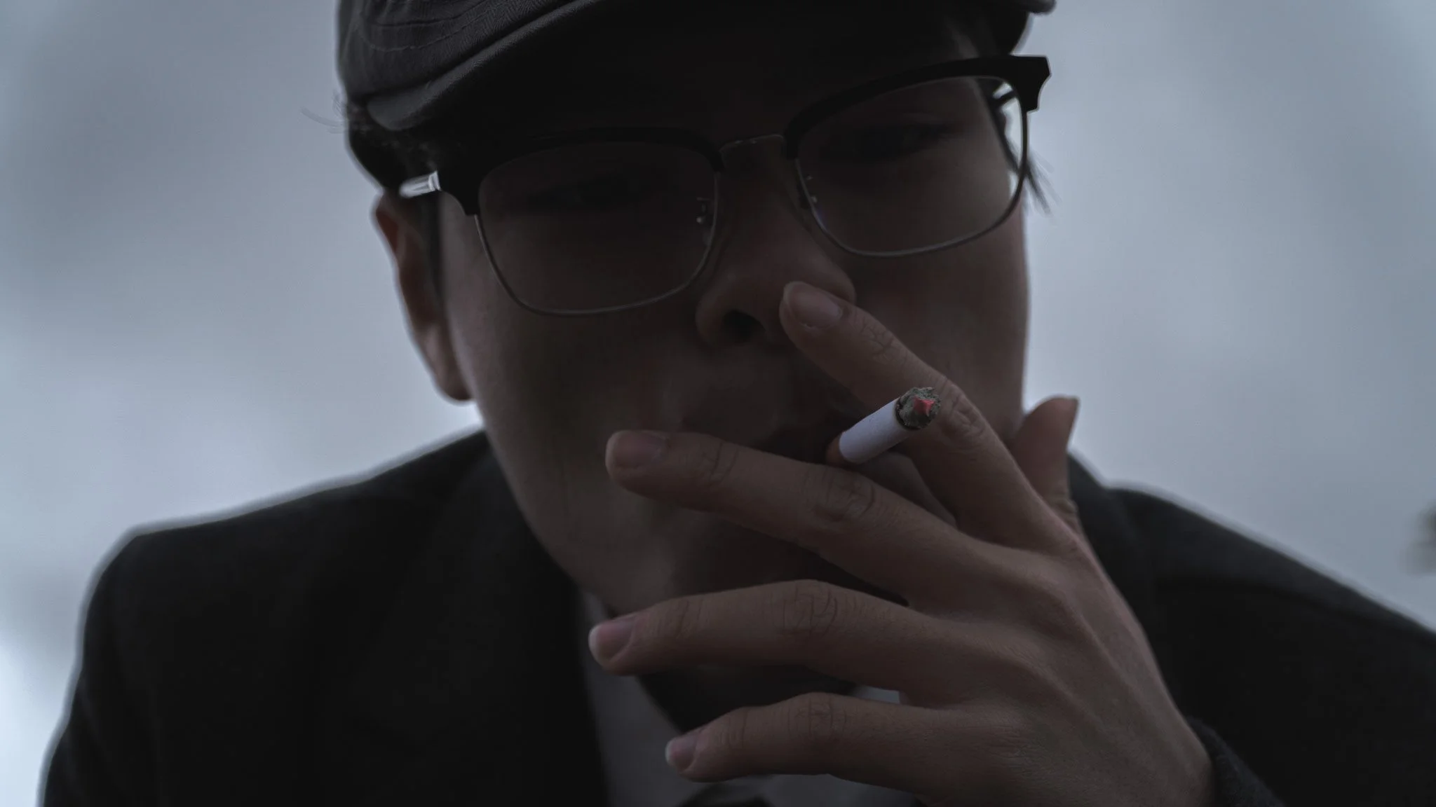 Close-up of a person with glasses smoking a cigarette.