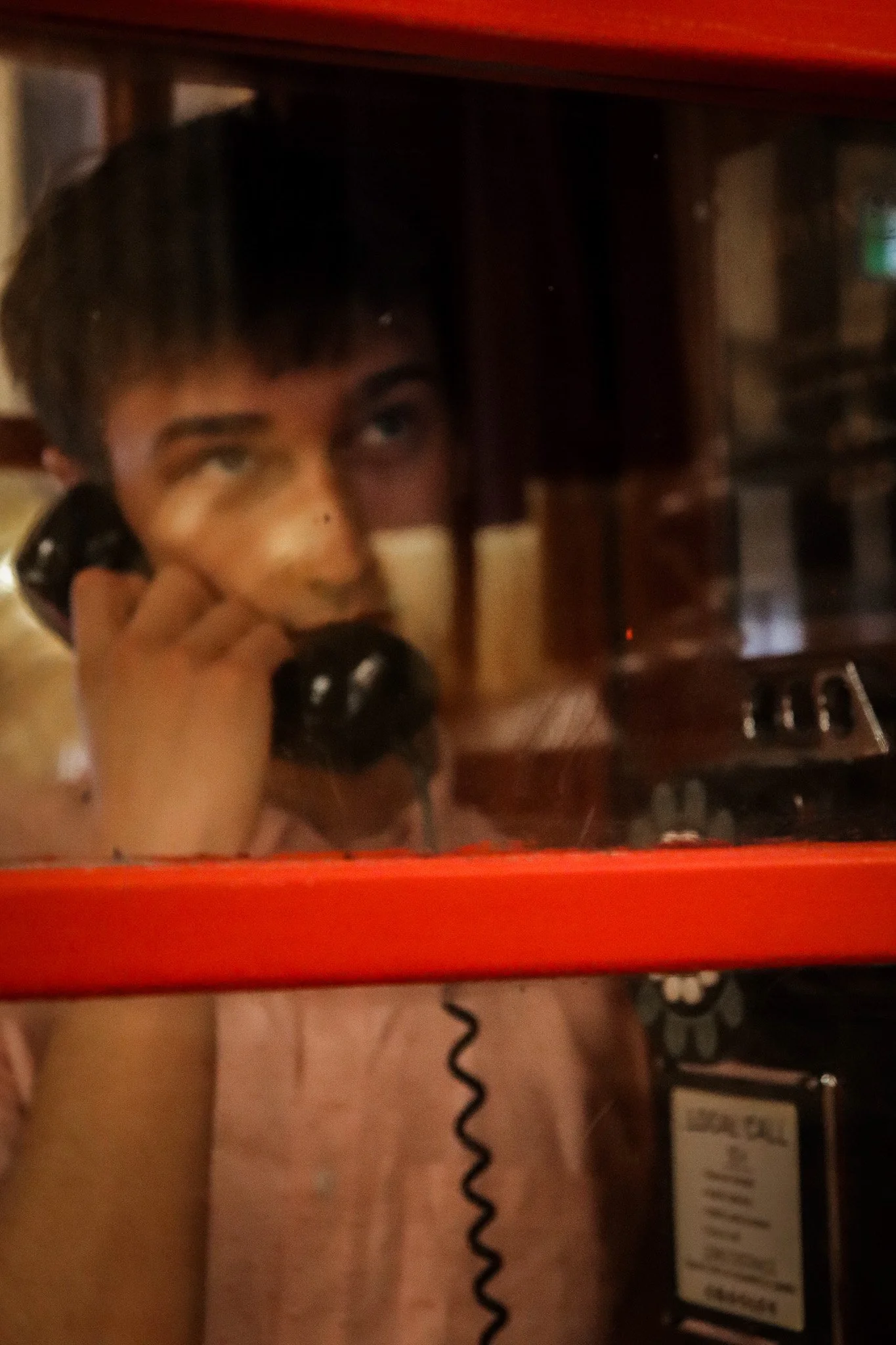 A person is taking a selfie with a vintage telephone in front of a mirror, with part of their body and tattoos visible.