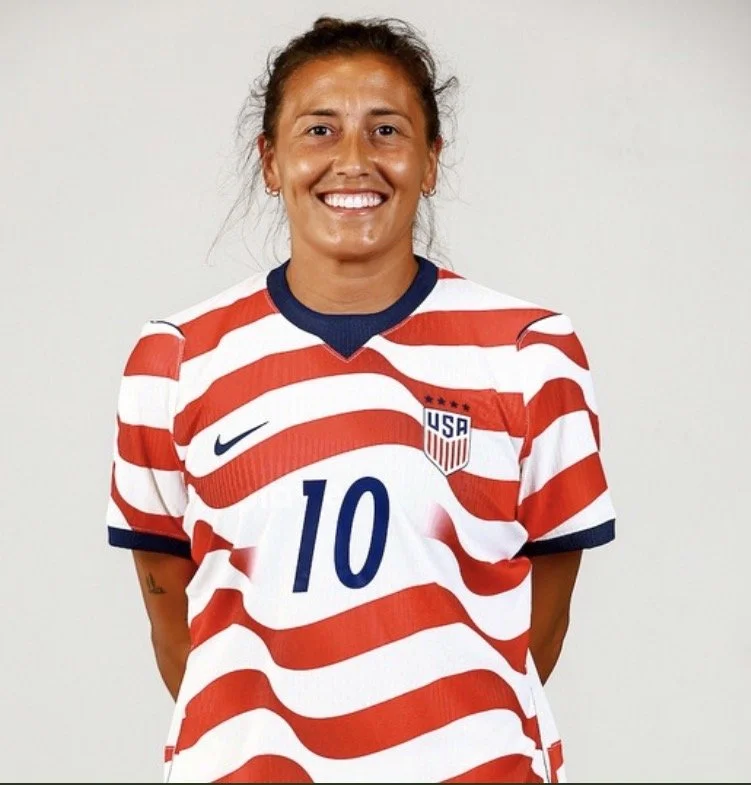 Female soccer player wearing a USA national team jersey with red and white stripes, the number 10, and the USA crest, smiling at the camera.