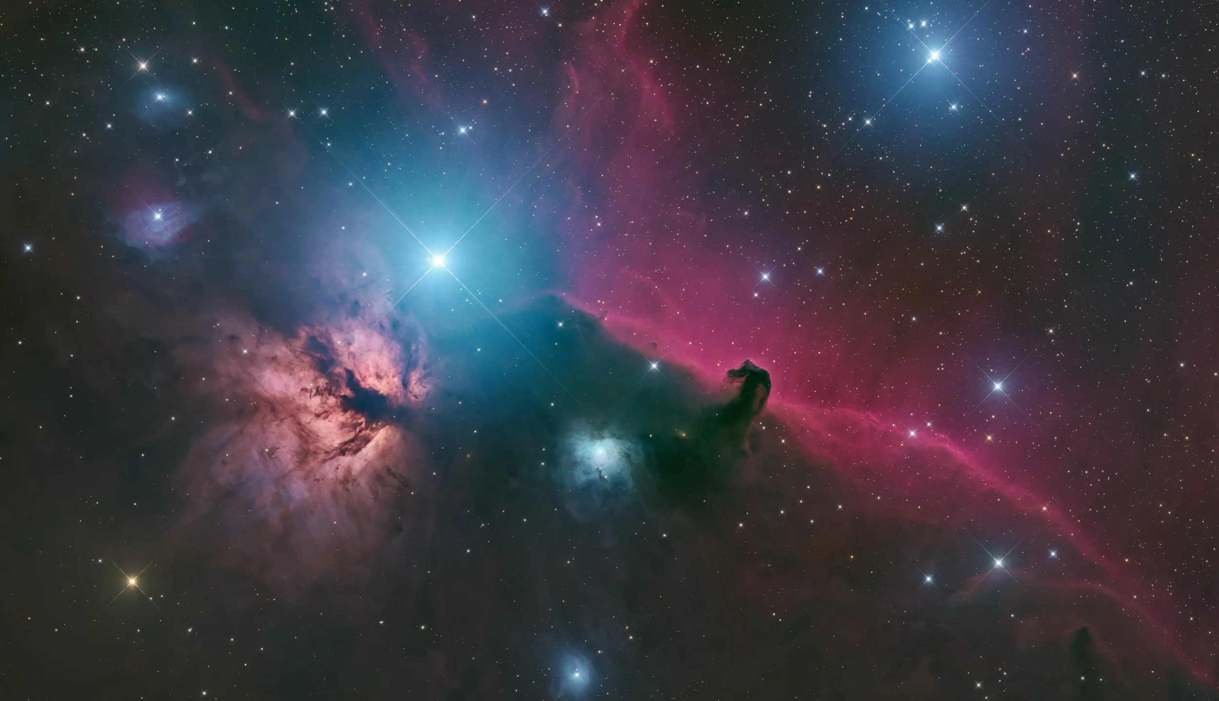 A colorful deep space nebula with bright stars and gas clouds in shades of blue, pink, and purple.