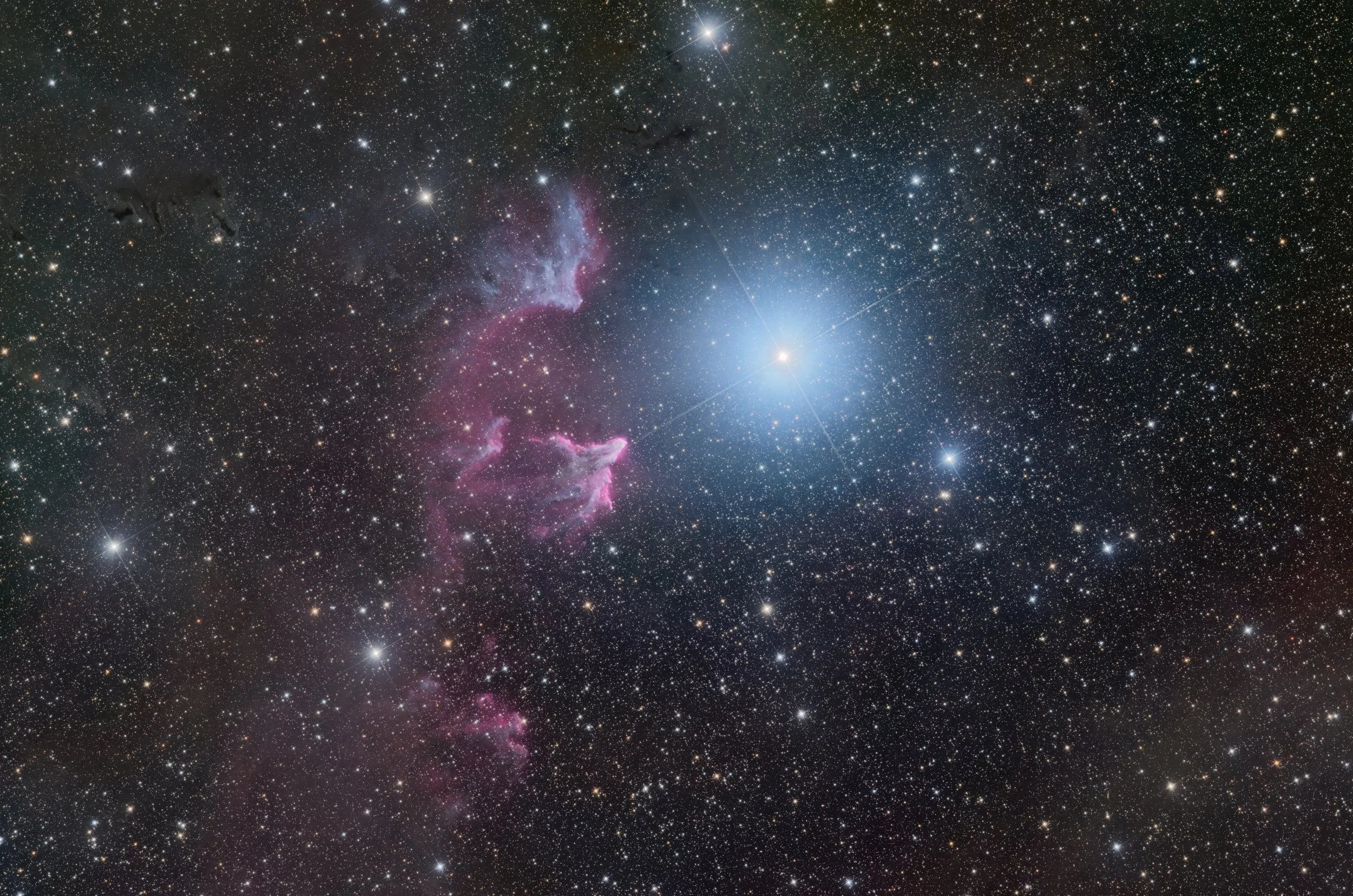 A detailed image of outer space showing numerous stars, nebulae, and cosmic dust, with a bright star or galaxy near the center, and various colorful clouds of gas and dust distributed across the scene.