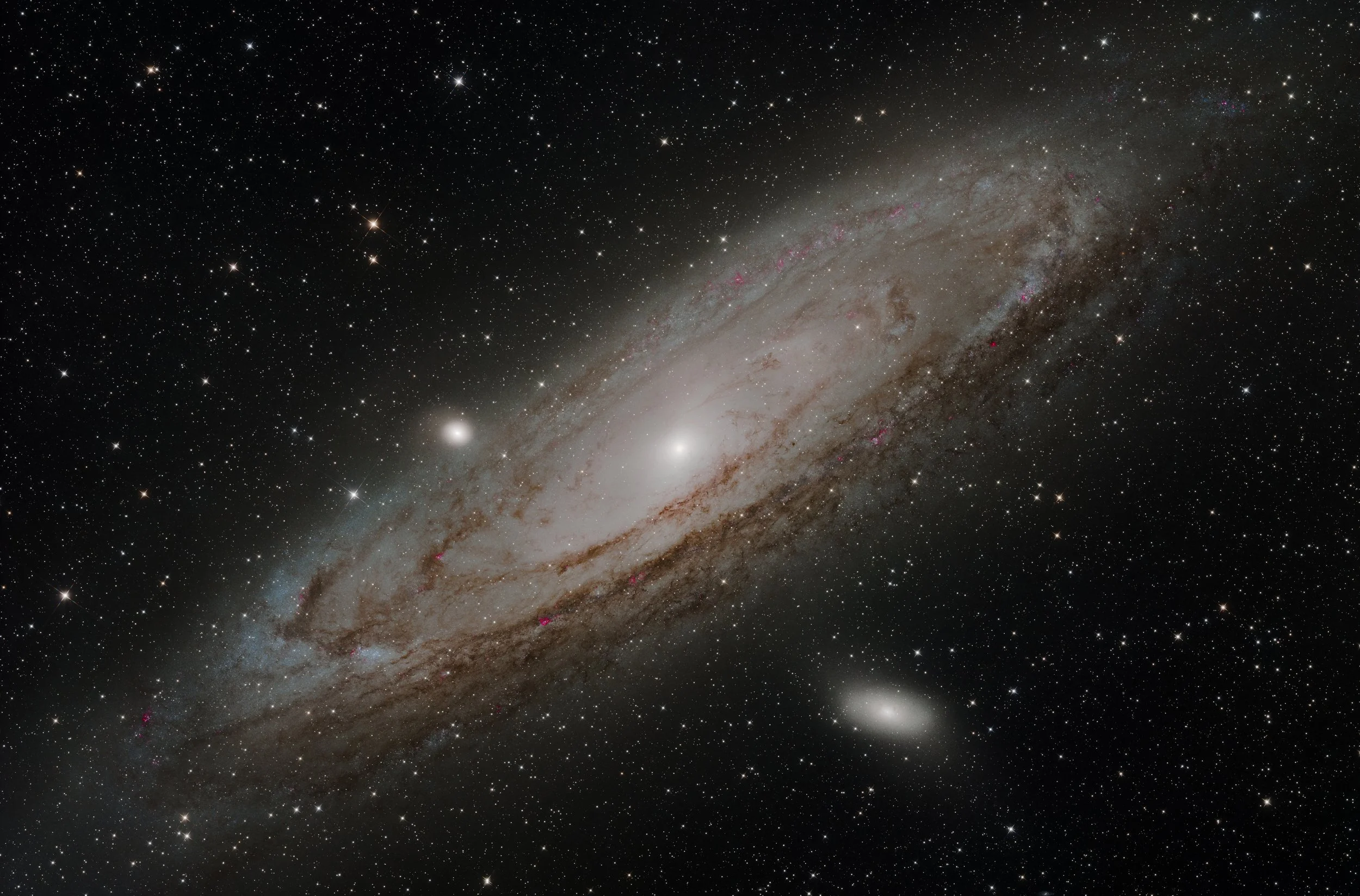 A detailed view of a galaxy with a bright core and spiral arms filled with stars, dust, and pinkish regions.