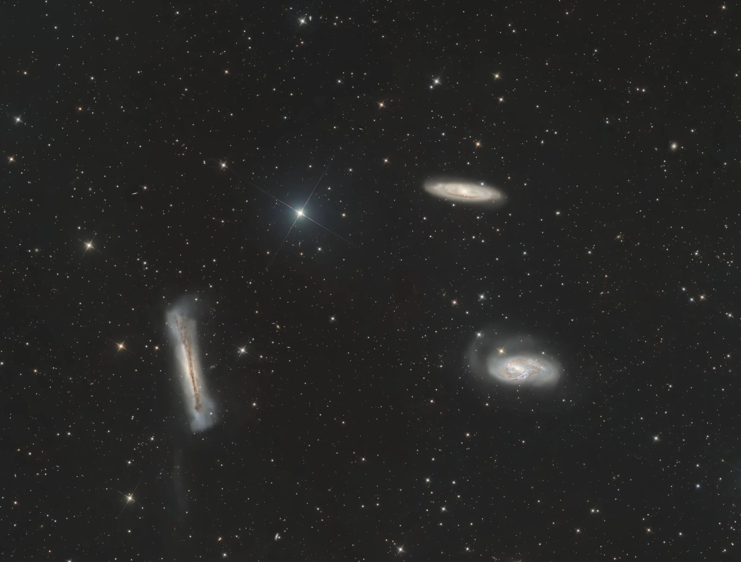 Deep space image showing numerous stars and galaxies, including a prominent spiral galaxy and a bright star with diffraction spikes.
