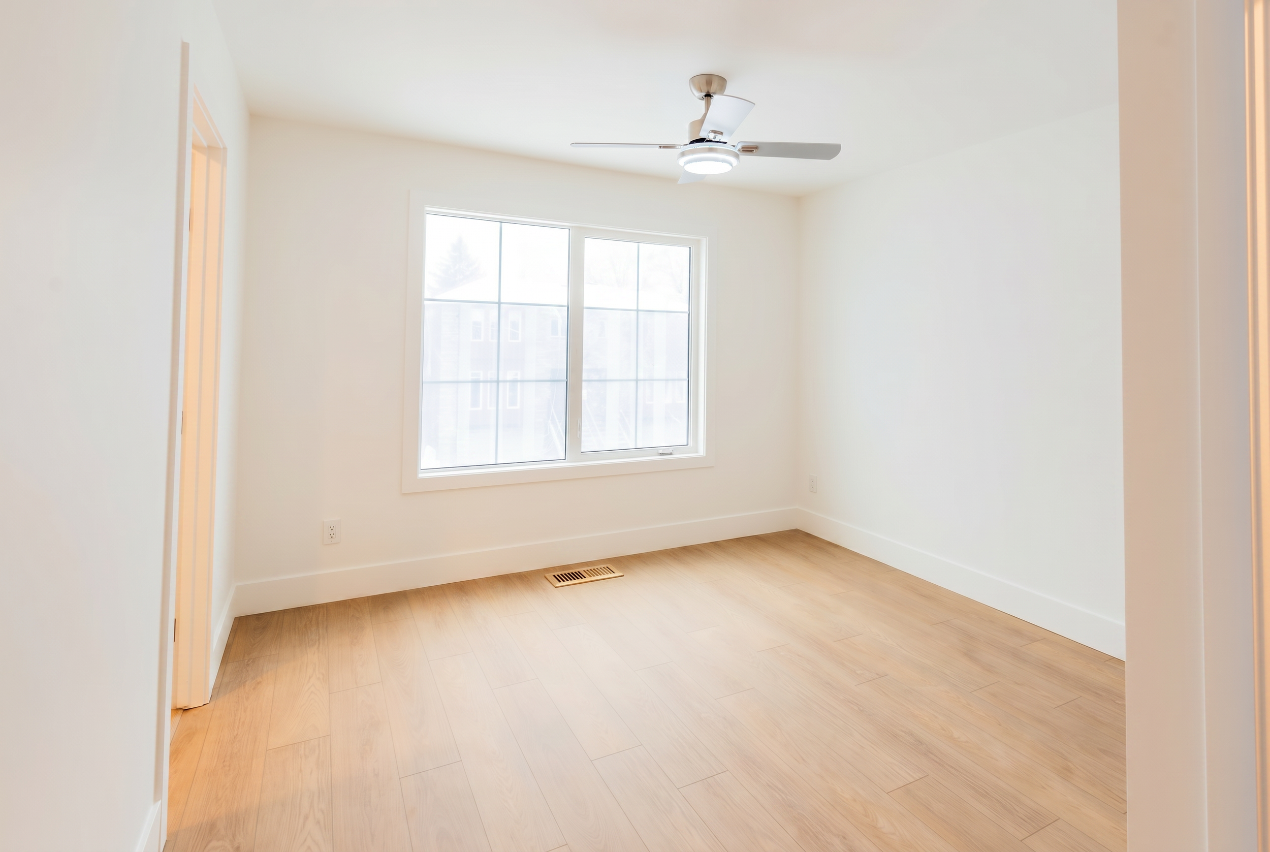 Bright bedroom with ceiling fan and large window in Unit 102 Uptown 17th Calgary 3-bedroom townhouse rental near 17th Ave SW by Suite Getaways