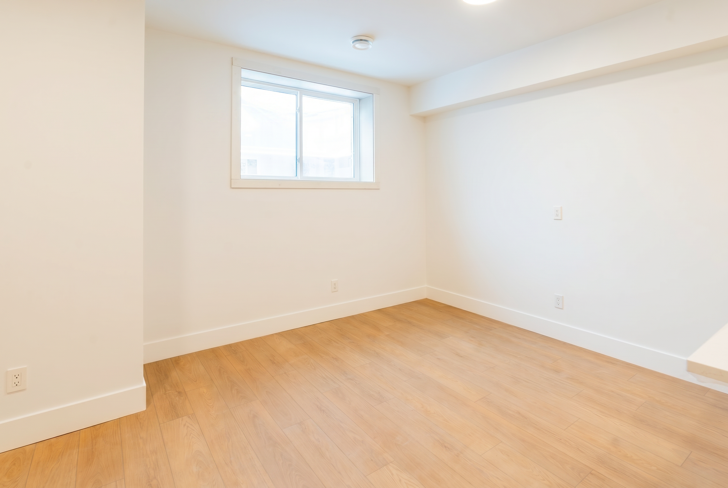 Bright bedroom with LVP flooring and window in Unit 104R Uptown 17th Calgary 1-bedroom lower suite rental near 17th Ave SW by Suite Getaways