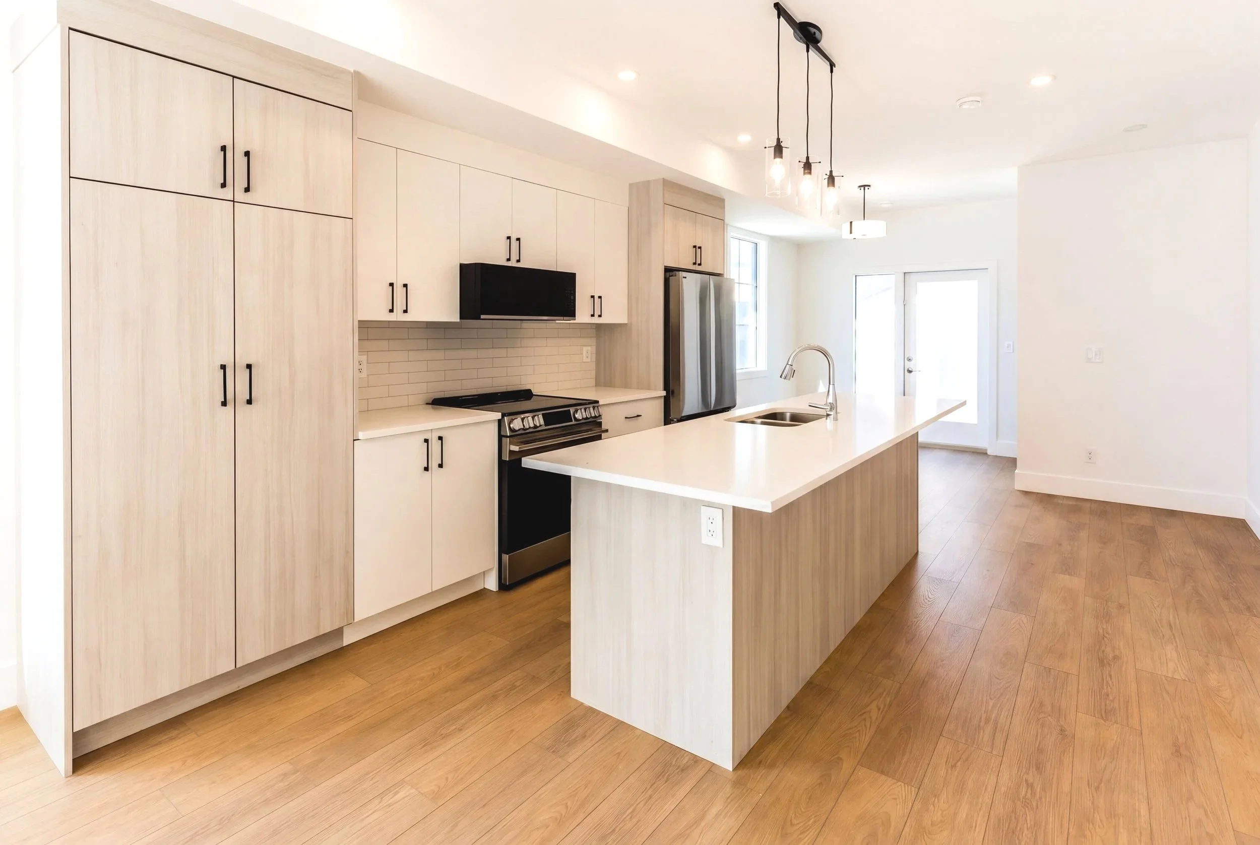 Unit 204 Uptown 17th Calgary 3-bed townhouse kitchen with pendant lights, white island and stainless steel appliances - available at Suite Getaways