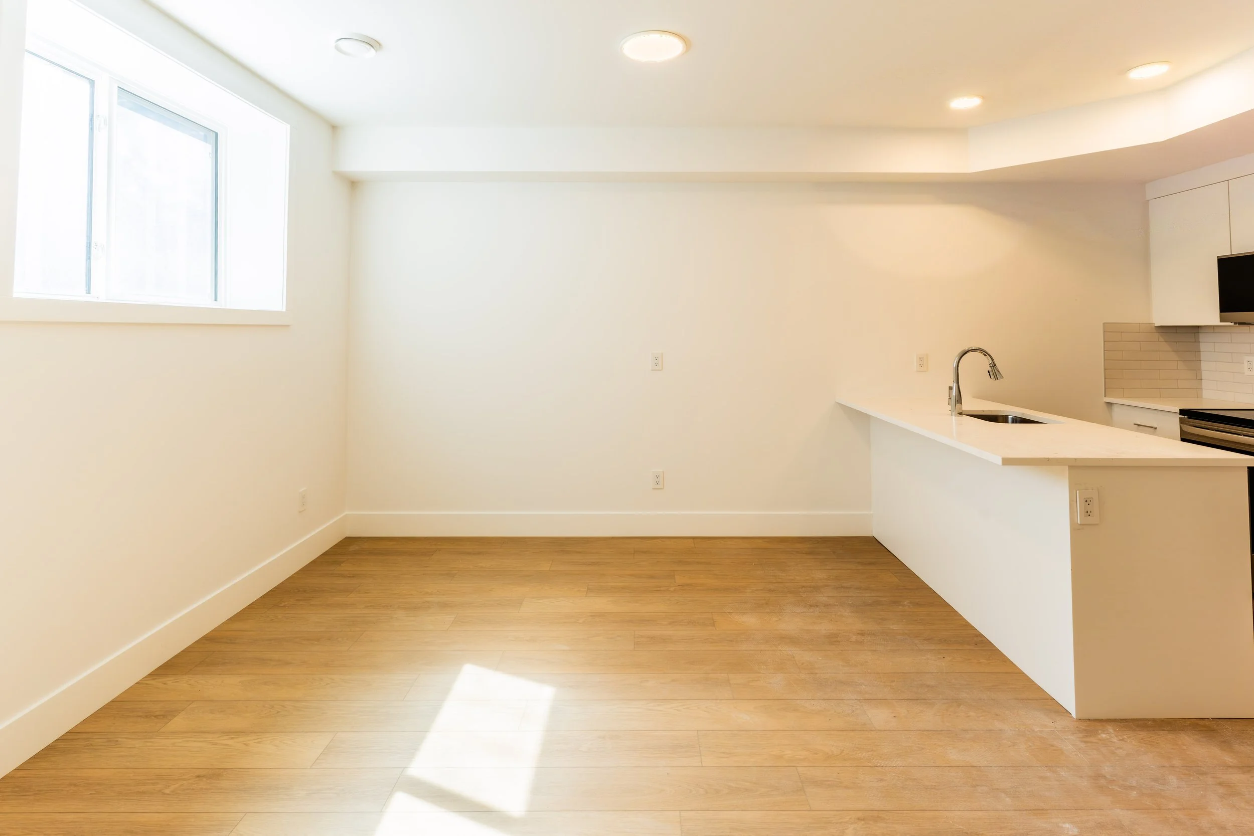 Bright lower suite room with large window and hardwood floors in Unit 204R Uptown 17th Calgary 1-bedroom lower suite rental near 17th Ave SW by Suite Getaways