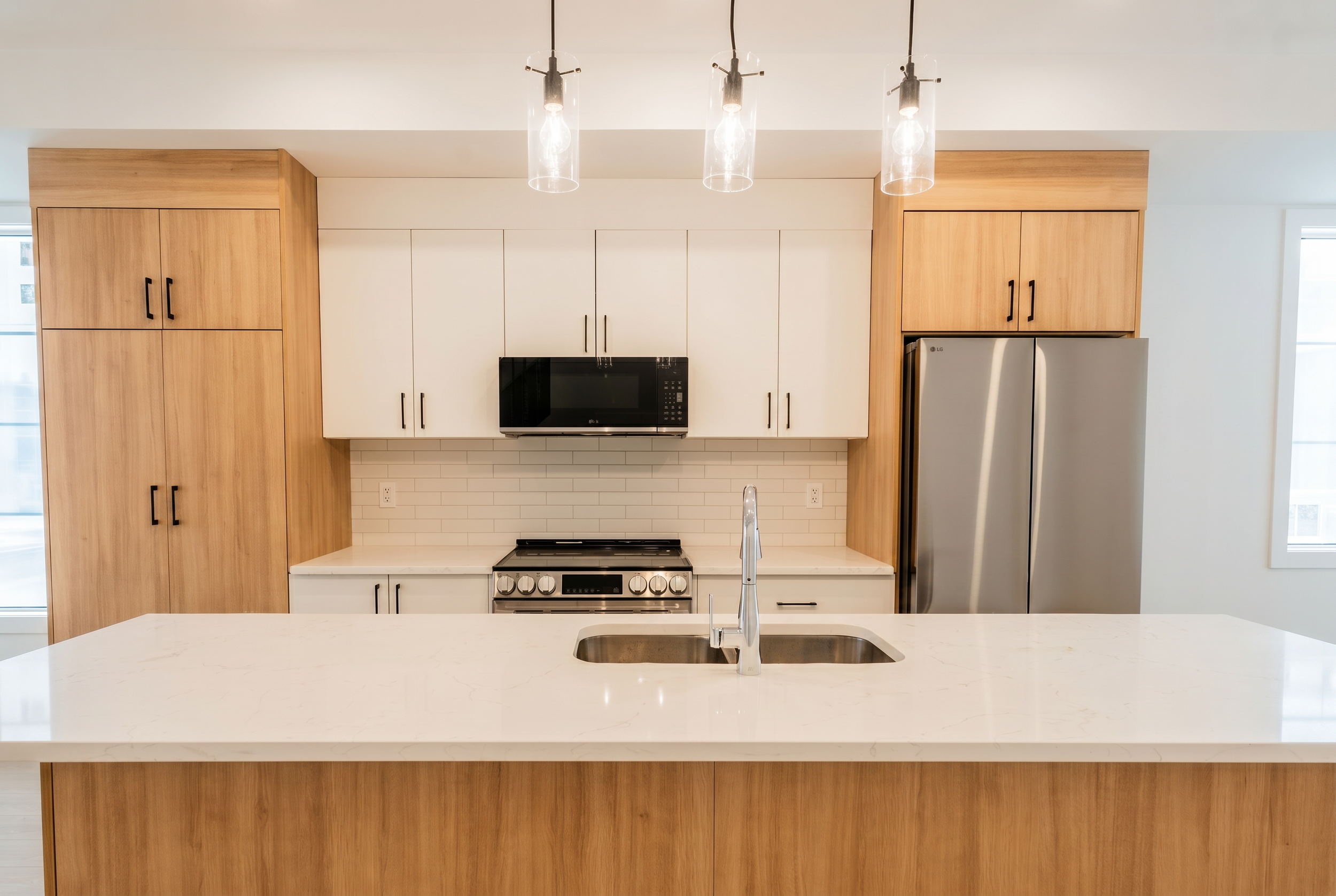 Modern kitchen with pendant lights, subway tile backsplash and LG stainless appliances in Unit 104 Uptown 17th Calgary townhouse rental by Suite Getaways