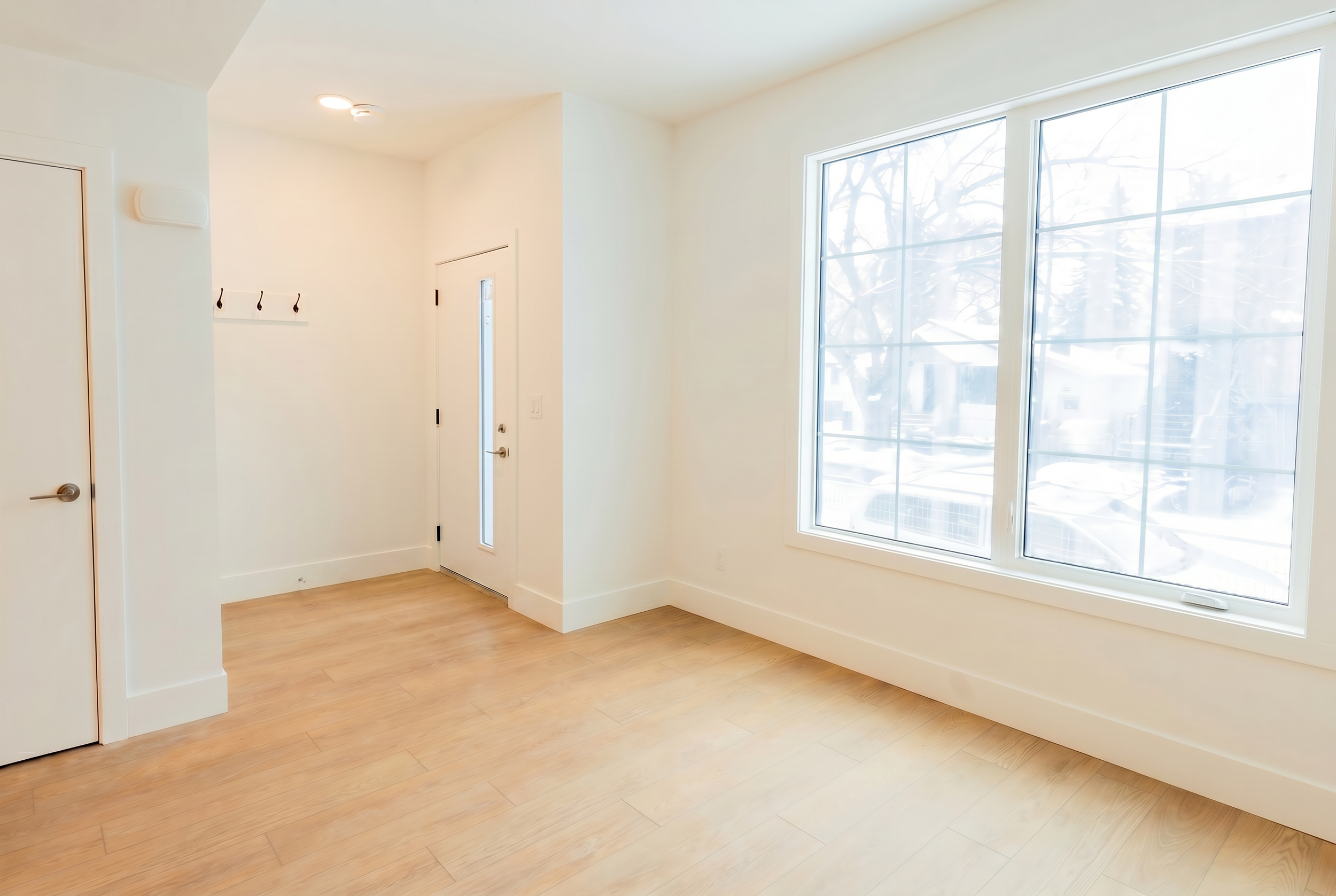 Bright mudroom entryway with coat hooks and large windows in Unit 102 Uptown 17th Calgary 3-bedroom townhouse near 17th Ave SW by Suite Getaways
