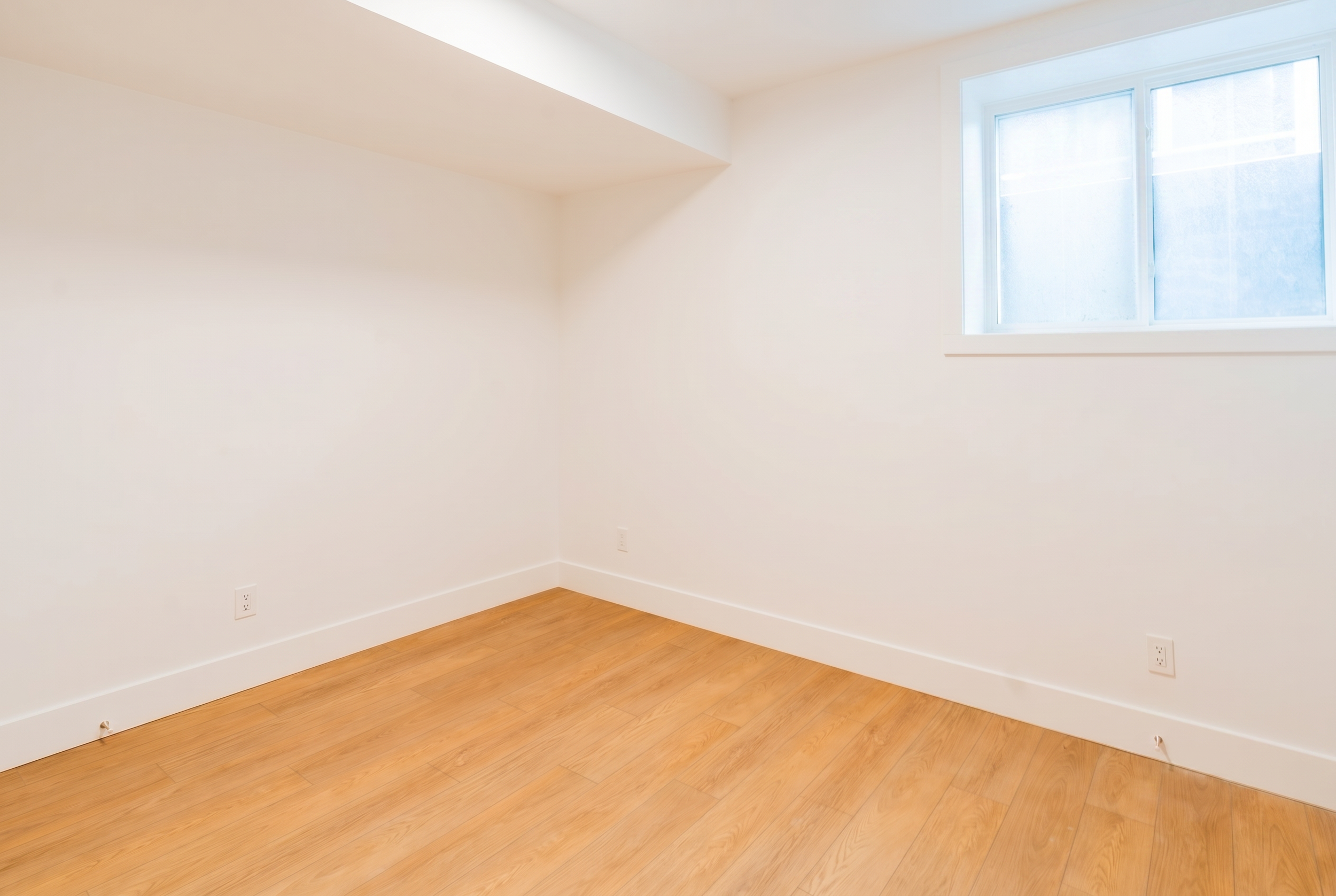 Bright bedroom with LVP flooring and window in Unit 101R Uptown 17th Calgary 1-bedroom lower suite rental near 17th Ave SW by Suite Getaways