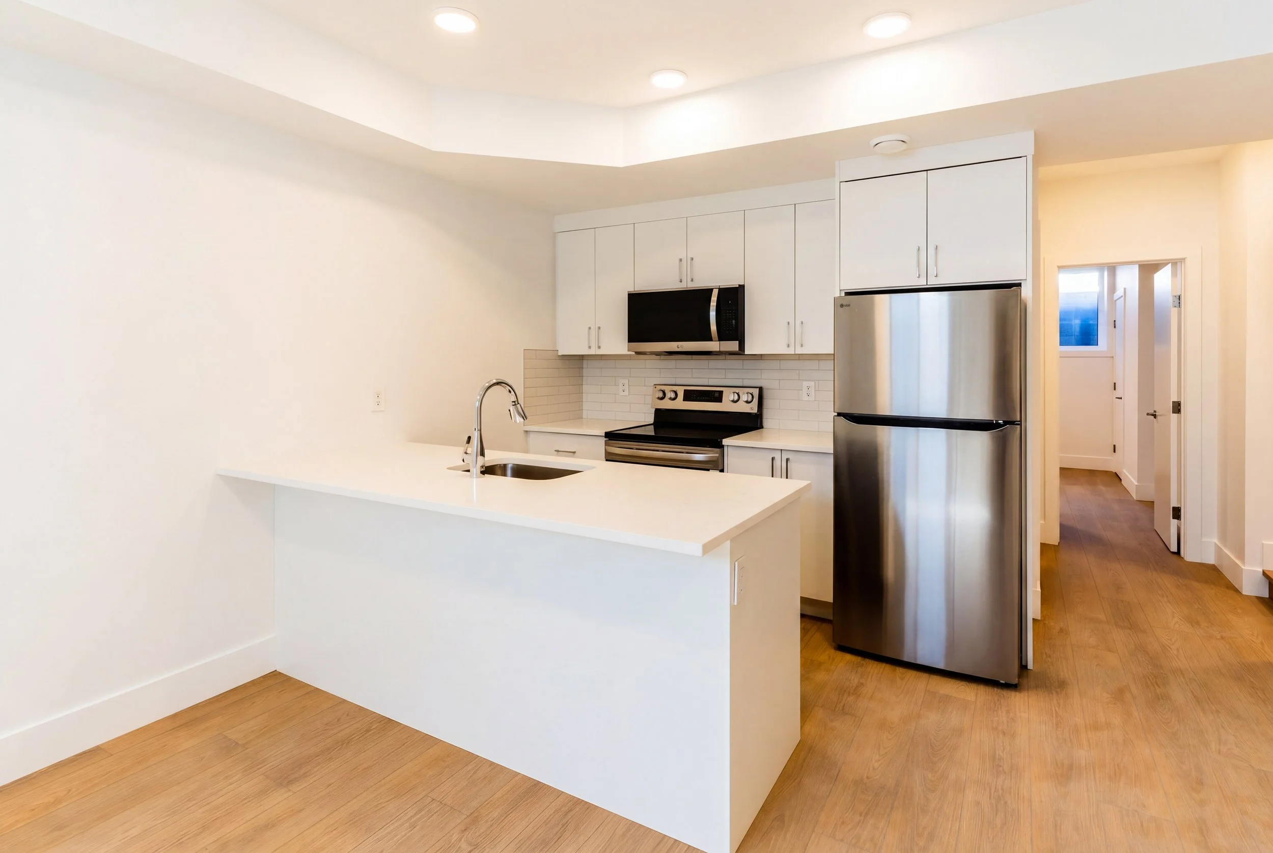 Modern kitchen with white cabinets and stainless steel appliances in Unit 202R Uptown 17th Calgary 1-bedroom lower suite rental near 17th Ave SW by Suite Getaways