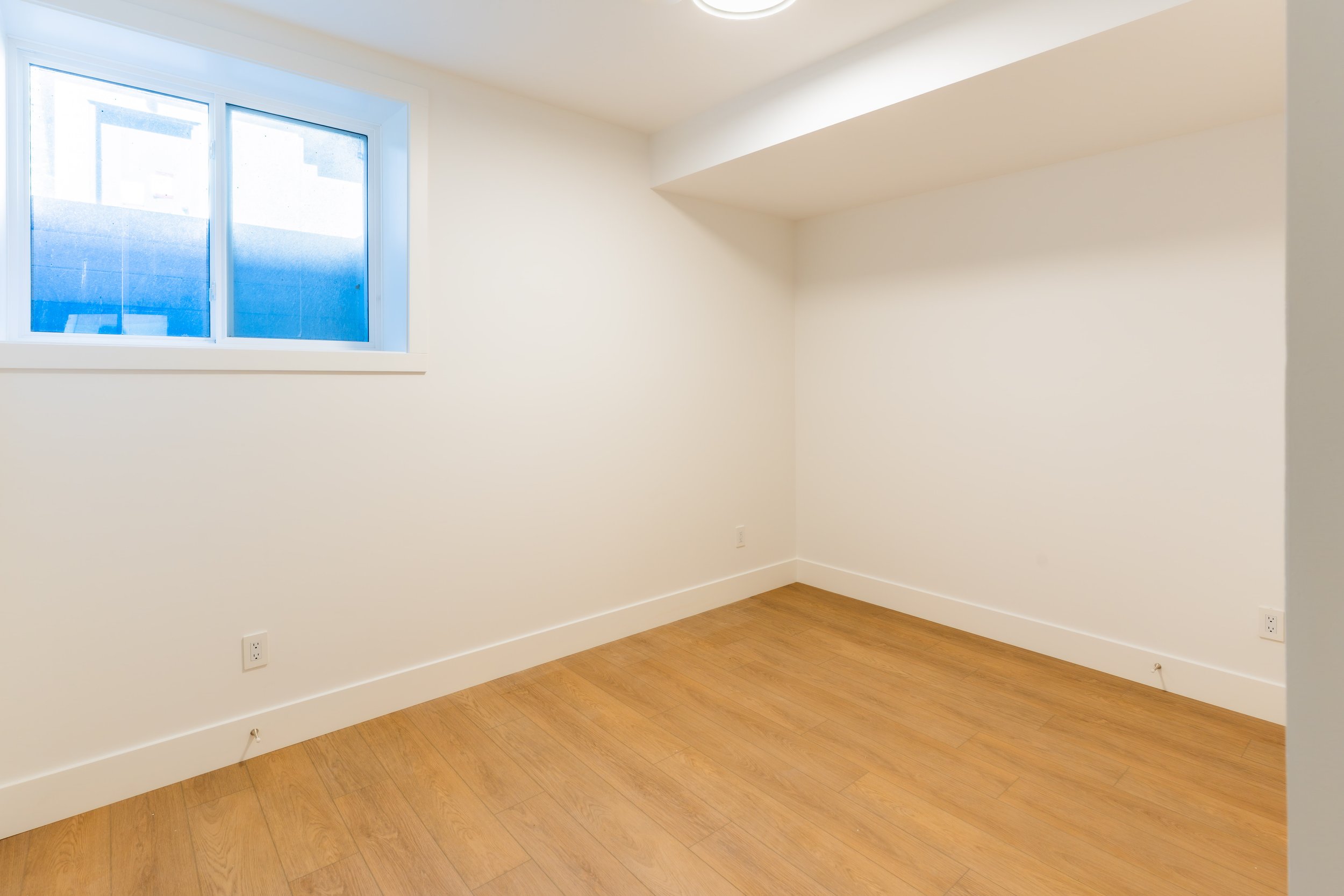 Spacious lower suite living area with window and hardwood floors in Unit 203R Uptown 17th Calgary 1-bedroom lower suite rental near 17th Ave SW by Suite Getaways
