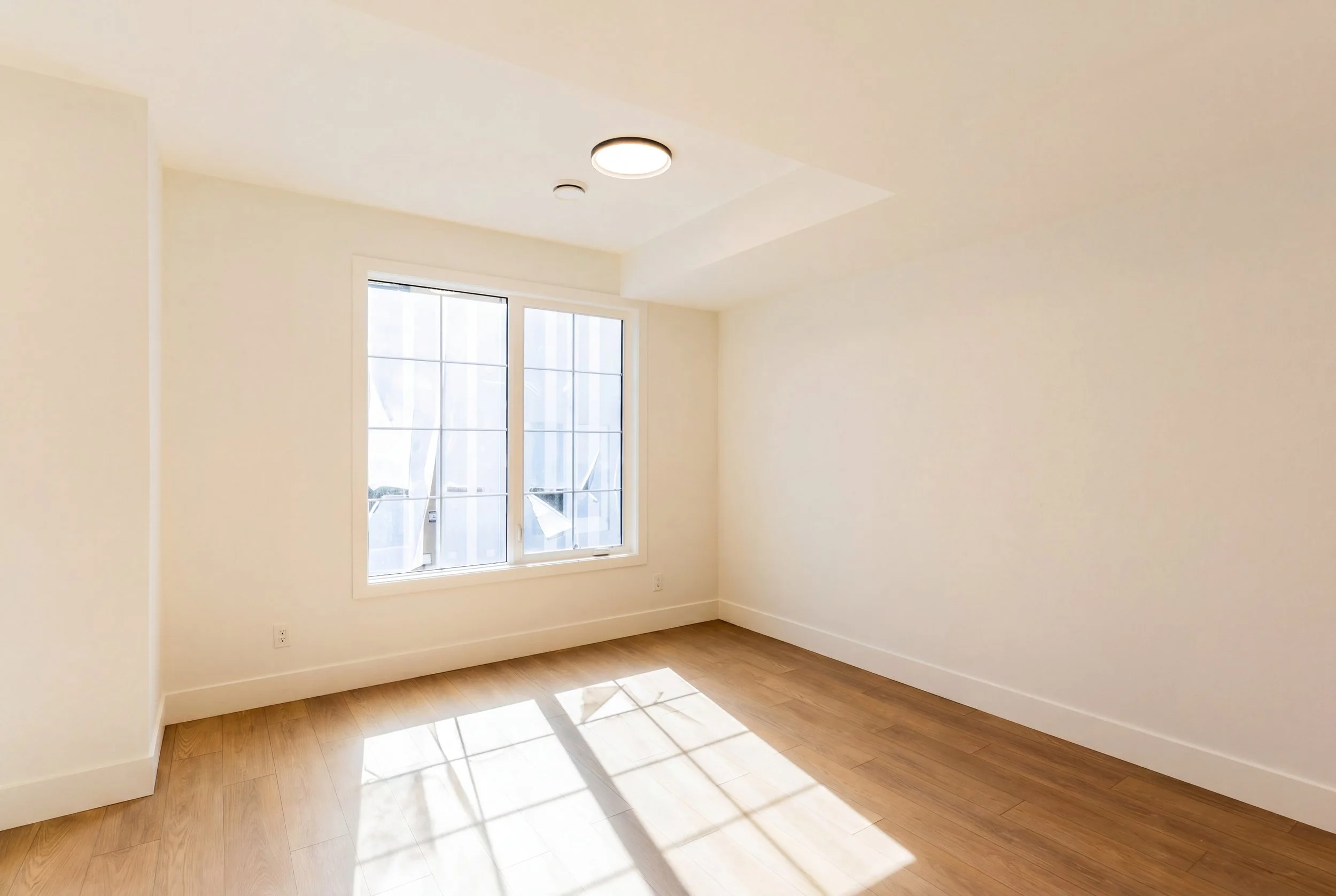 Unit 202 Uptown 17th Calgary 3-bed townhouse bright bedroom with large windows and hardwood floors - available at Suite Getaways
