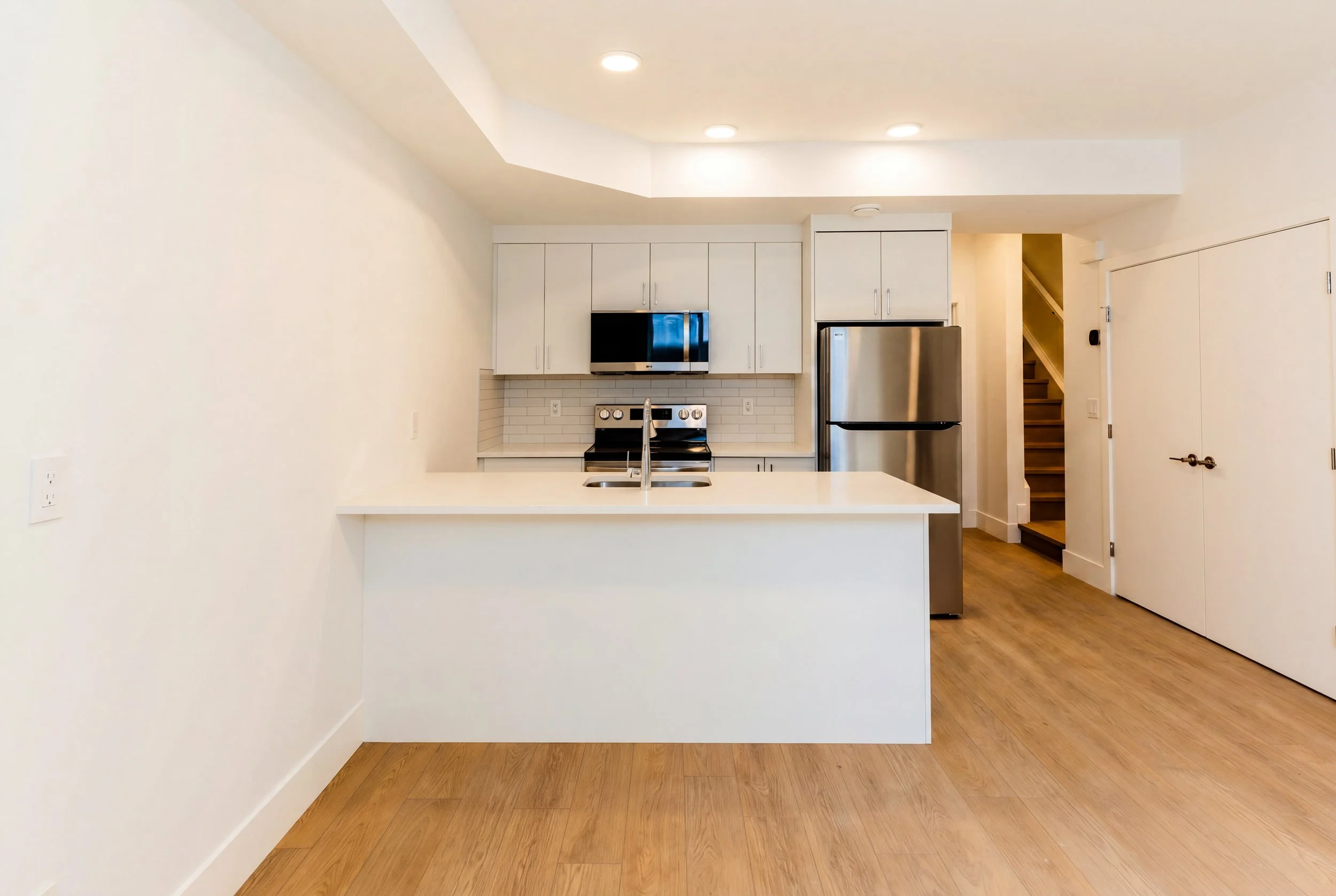 Open kitchen with white cabinets and stainless appliances in Unit 202R Uptown 17th Calgary 1-bedroom lower suite rental near 17th Ave SW by Suite Getaways