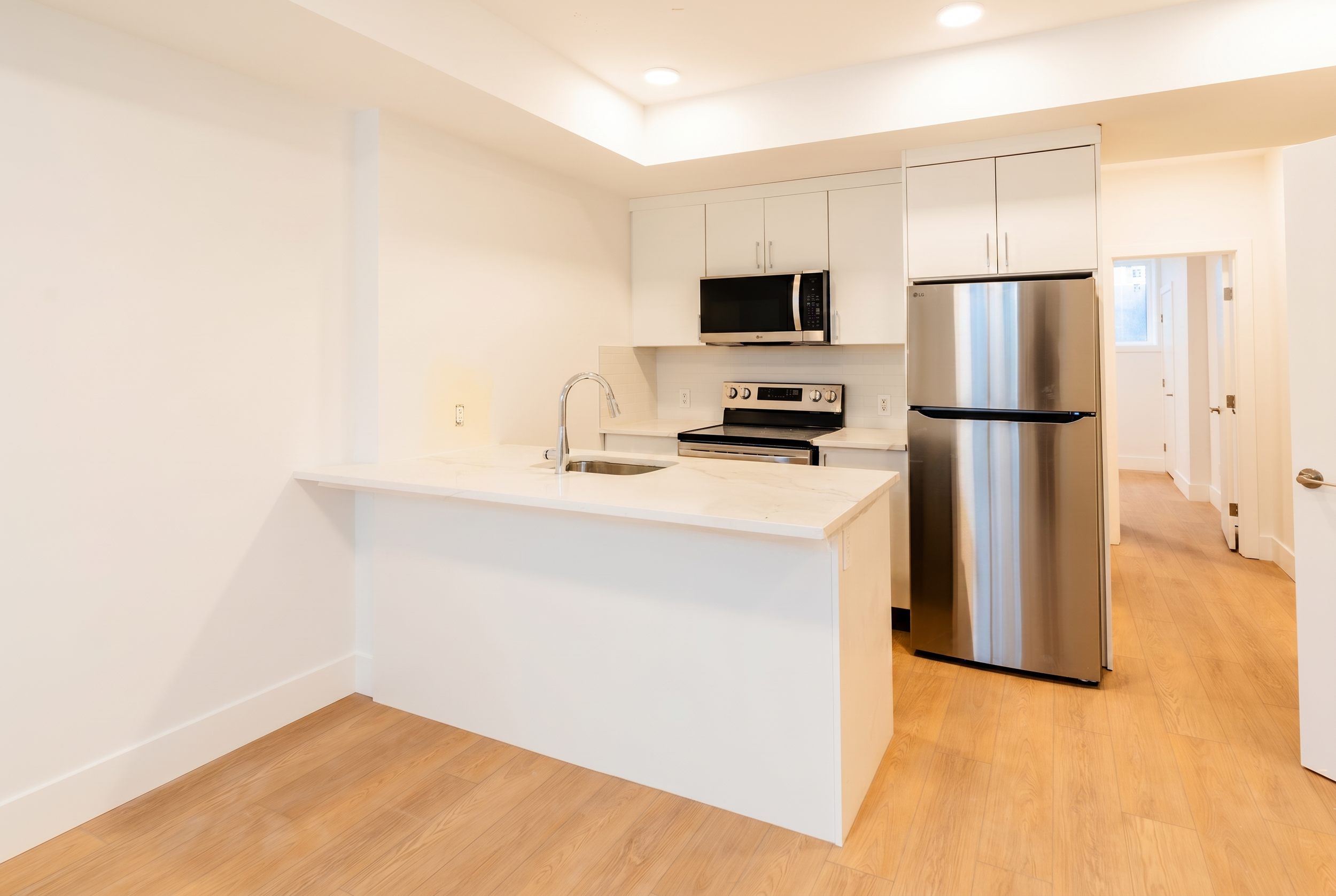 Open-concept kitchen with LG stainless appliances in Unit 101R Uptown 17th Calgary 1-bedroom lower suite rental near 17th Ave SW by Suite Getaways