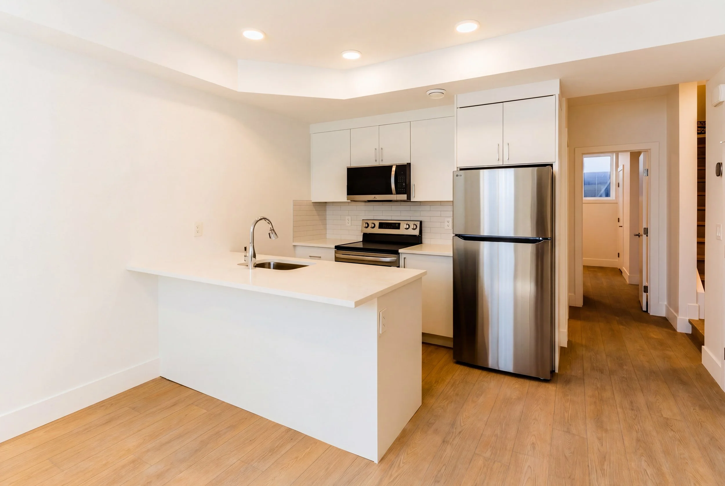 Modern kitchen with white cabinets stainless steel appliances and island in Unit 204R Uptown 17th Calgary 1-bedroom lower suite rental near 17th Ave SW by Suite Getaways