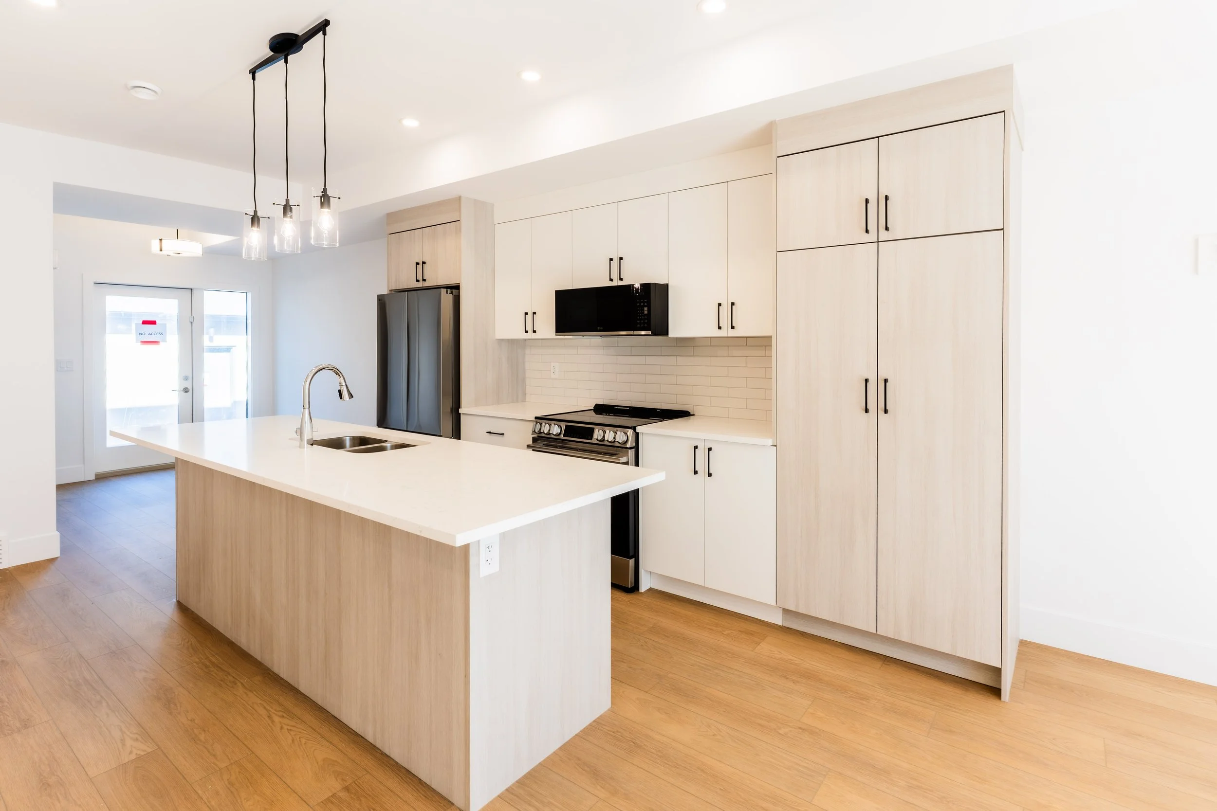 Unit 203 Uptown 17th Calgary 3-bed townhouse kitchen close-up with white quartz island, pendant lighting and stainless steel appliances - available at Suite Getaways