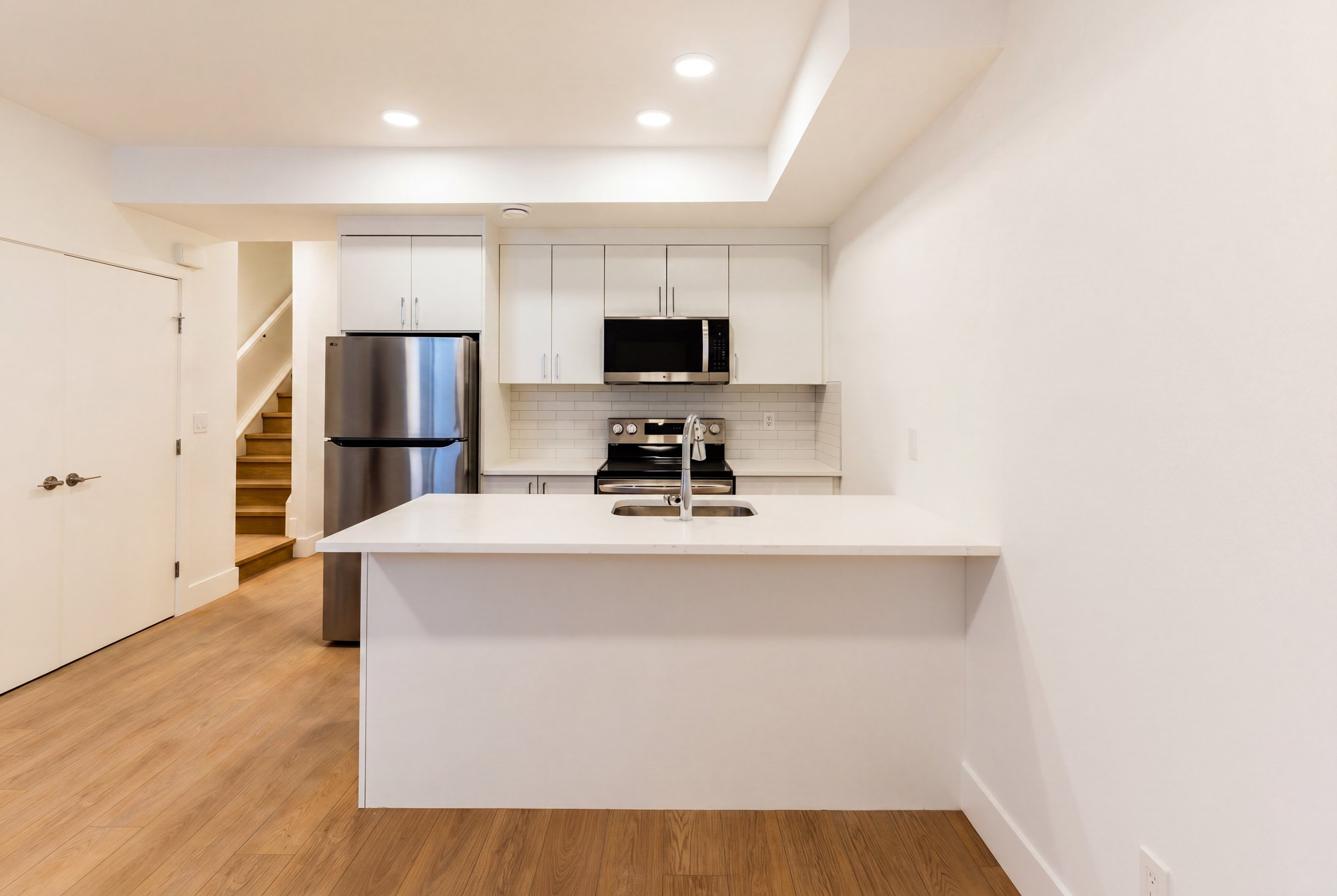 Modern kitchen with white cabinets and stainless steel appliances in Unit 203R Uptown 17th Calgary 1-bedroom lower suite rental near 17th Ave SW by Suite Getaways