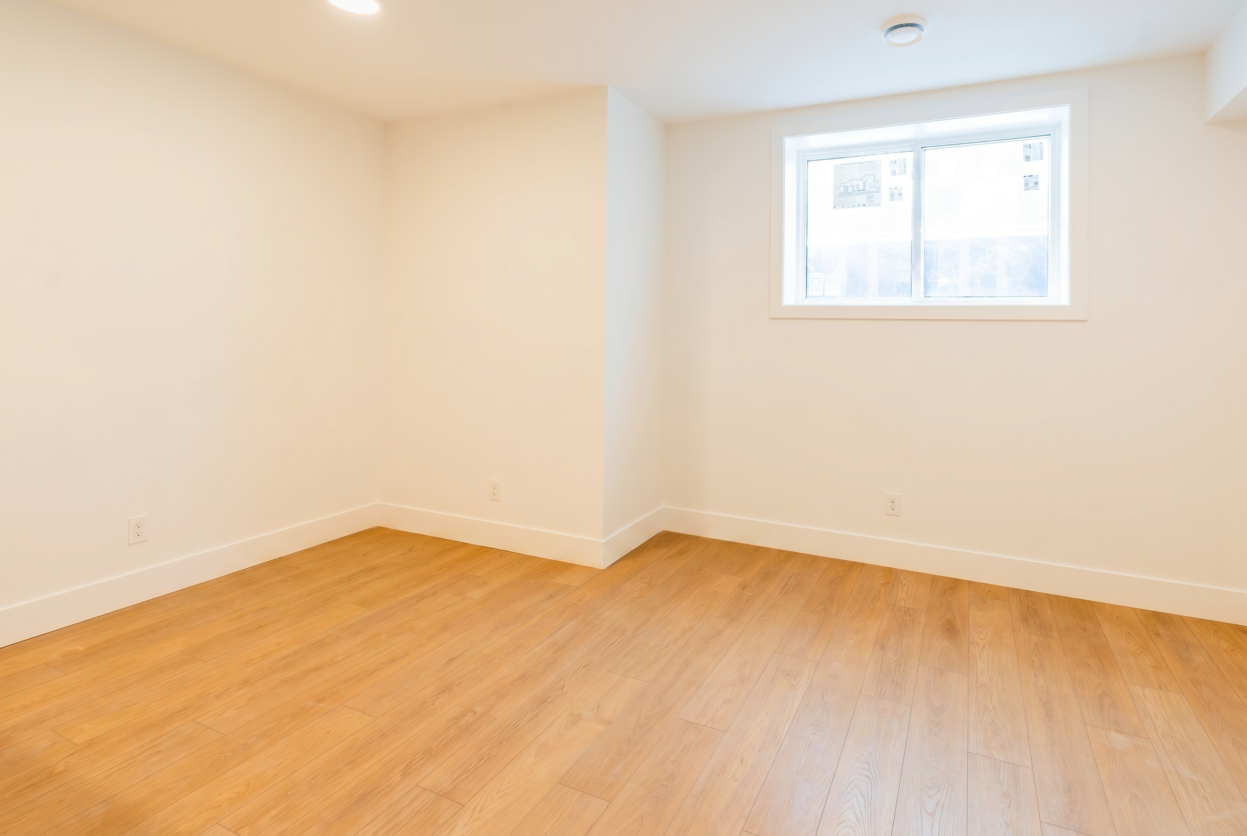 Bright bedroom with LVP flooring and window in Unit 103R Uptown 17th Calgary 1-bedroom lower suite rental near 17th Ave SW by Suite Getaways