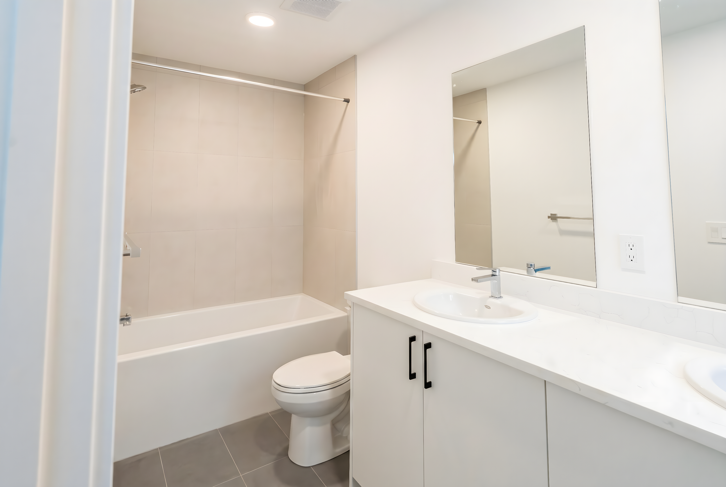 Modern bathroom with full bathtub, toilet and white vanity at Uptown 17th Calgary rental suites near 17th Ave SW by Suite Getaways