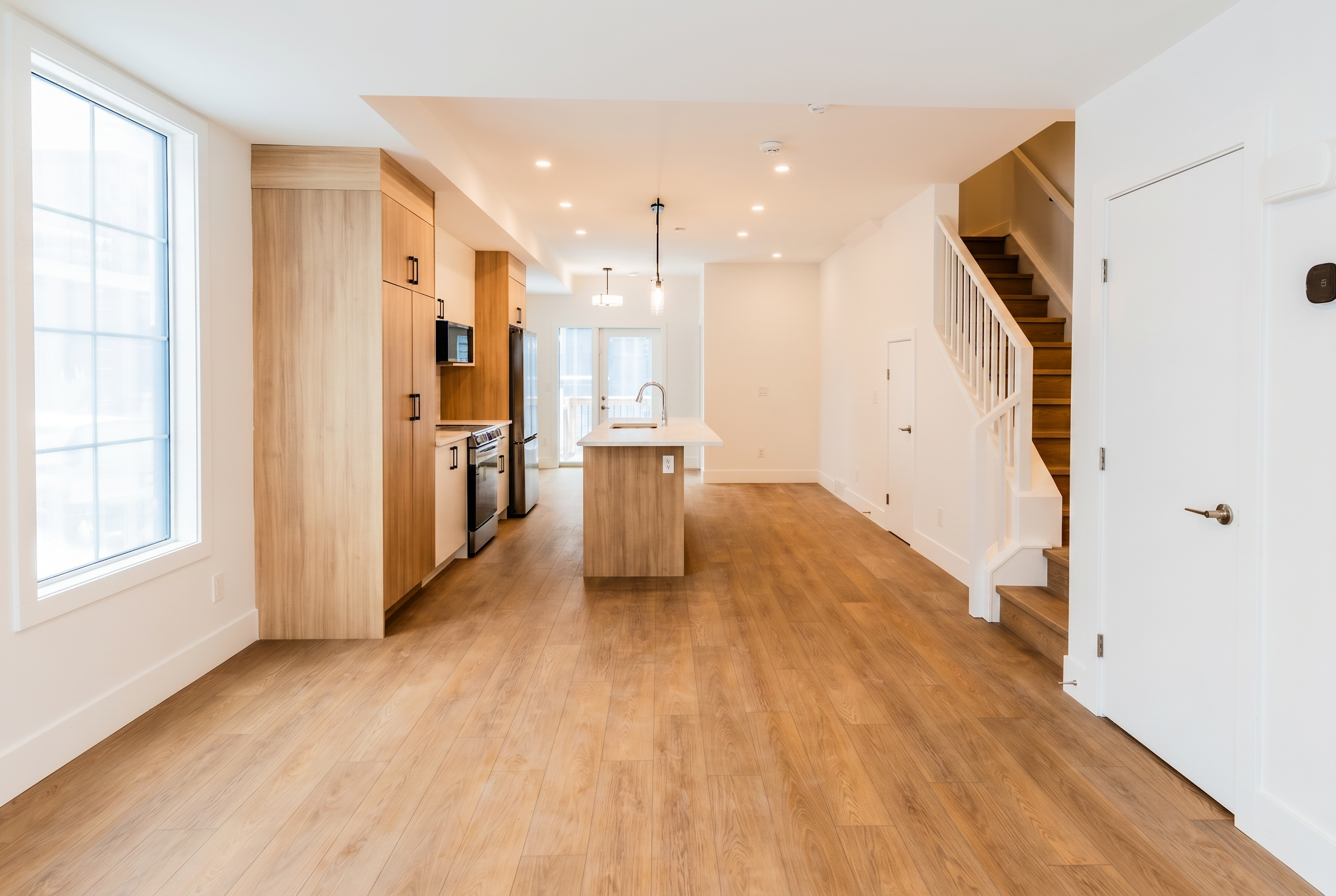 Open-concept kitchen and living area with staircase in Unit 104 Uptown 17th Calgary 3-bedroom townhouse rental near 17th Ave SW by Suite Getaways