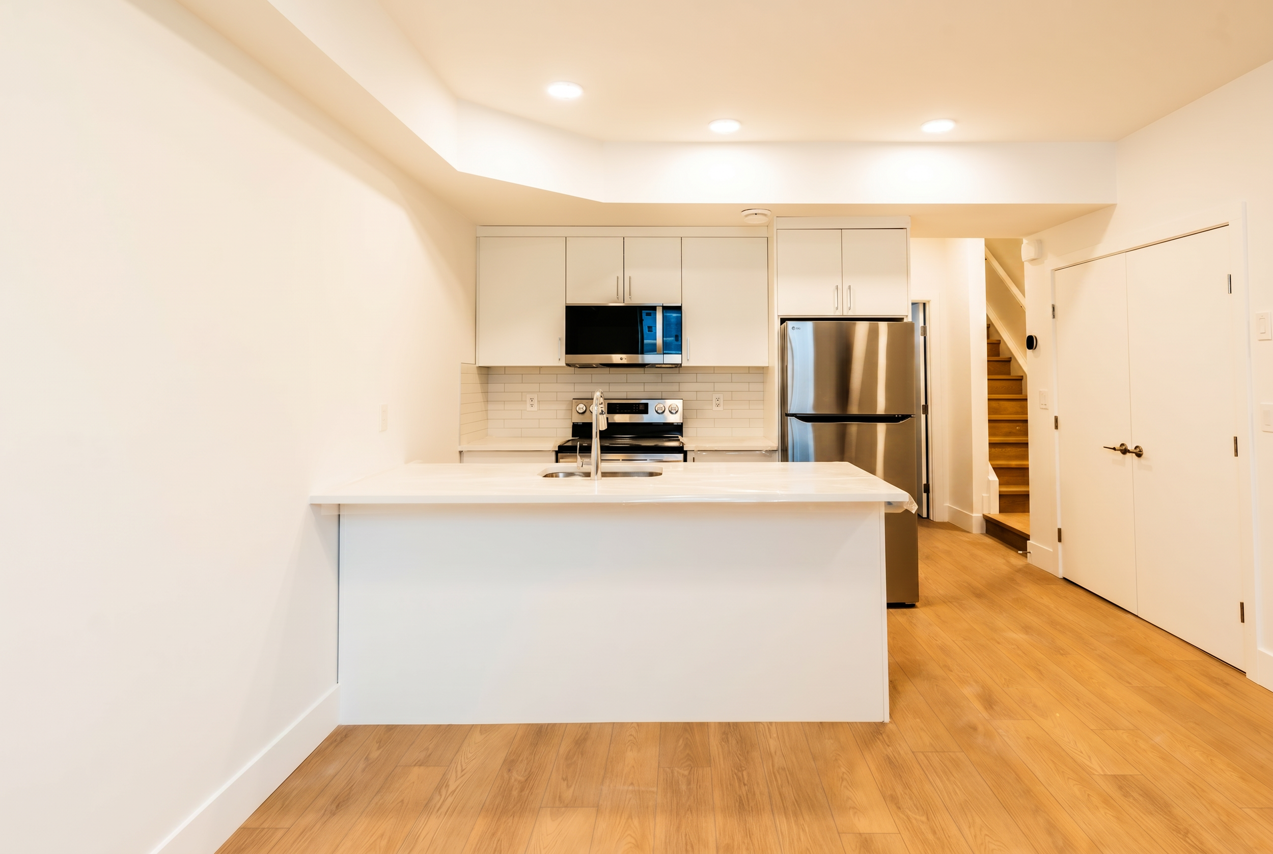 Kitchen with white cabinets and LG appliances with hallway view in Unit 104R Uptown 17th Calgary 1-bedroom lower suite rental near 17th Ave SW by Suite Getaways