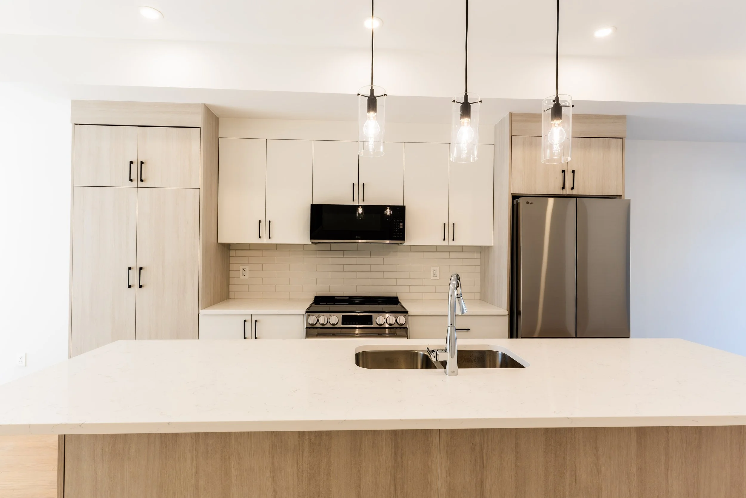 Unit 202 Uptown 17th Calgary 3-bed townhouse white kitchen with pendant lighting and stainless appliances - available at Suite Getaways
