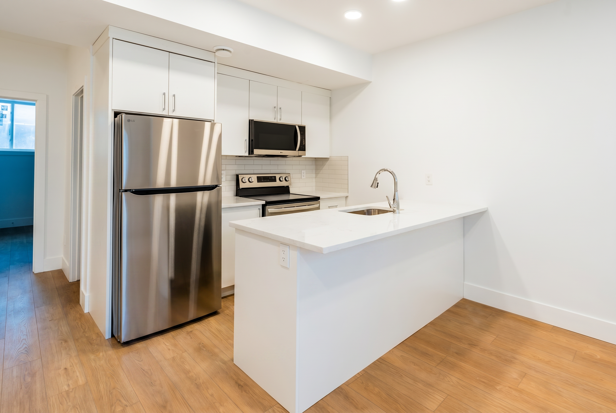 Kitchen with white cabinets and LG stainless appliances in Unit 103R Uptown 17th Calgary 1-bedroom lower suite rental near 17th Ave SW by Suite Getaways