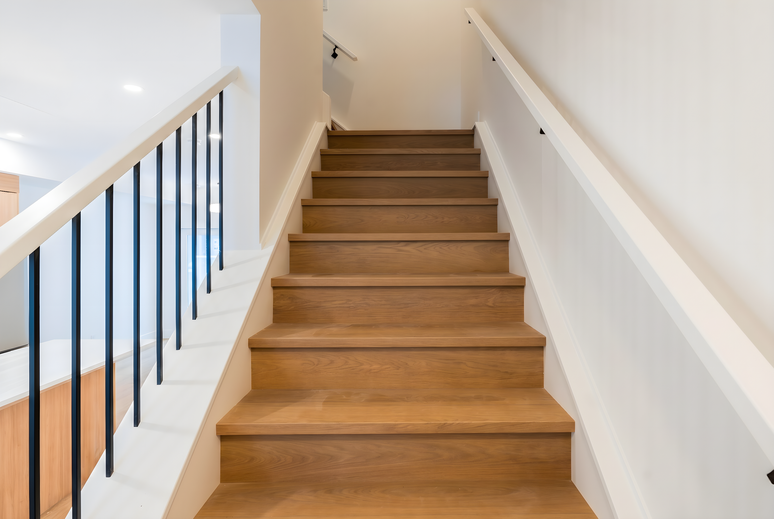 Natural wood staircase with black metal railings at Uptown 17th Calgary townhouse rental suites near 17th Ave SW by Suite Getaways