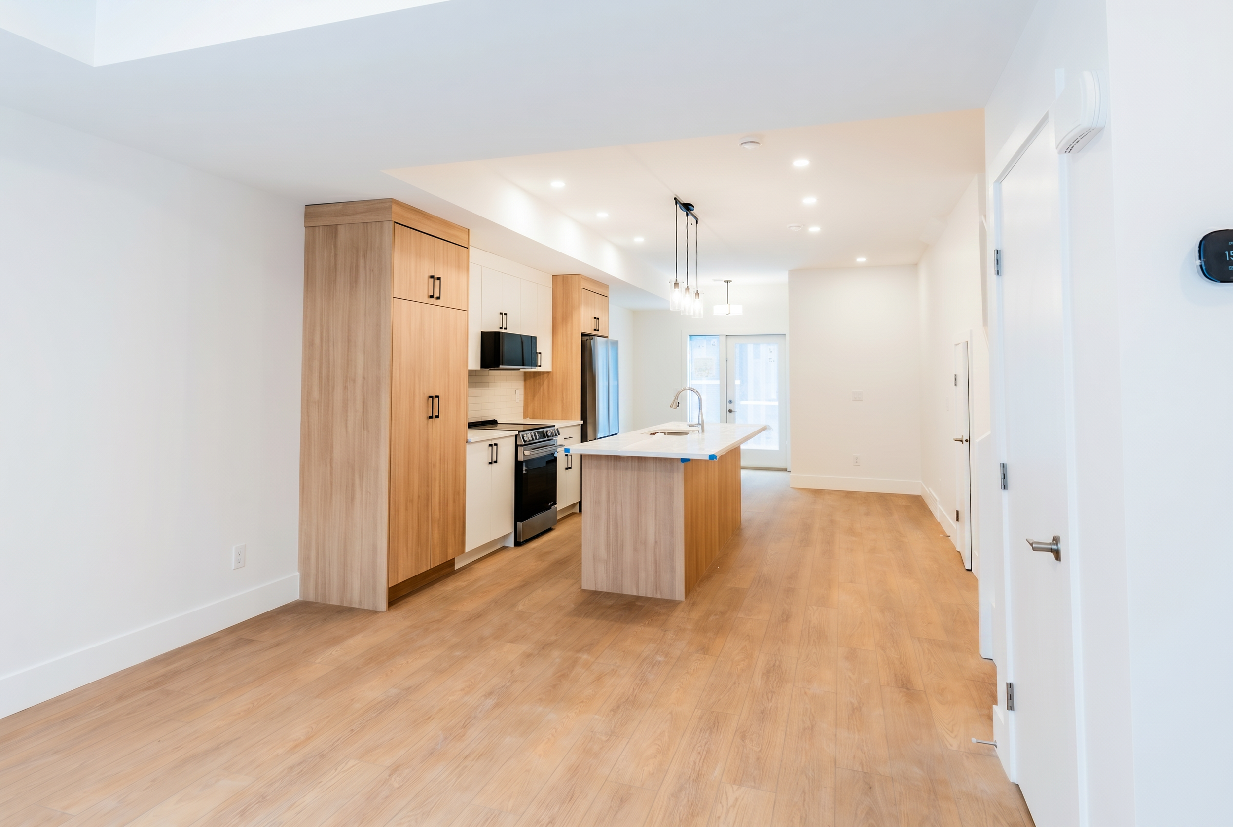 Open-concept kitchen with pendant lights and LG appliances in Unit 102 Uptown 17th Calgary 3-bedroom townhouse by Suite Getaways