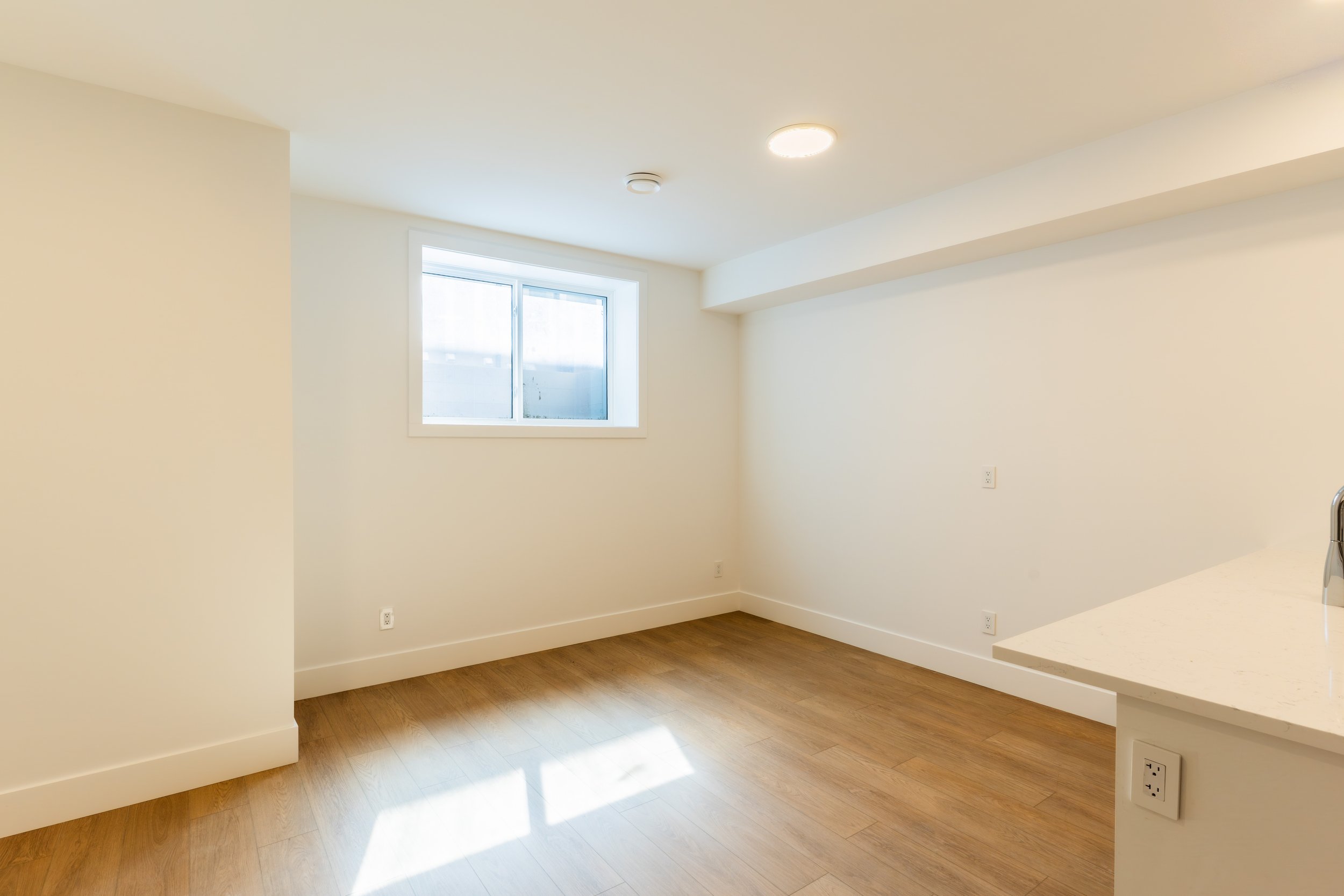 Spacious bedroom with window and hardwood floors in Unit 202R Uptown 17th Calgary 1-bedroom lower suite rental near 17th Ave SW by Suite Getaways