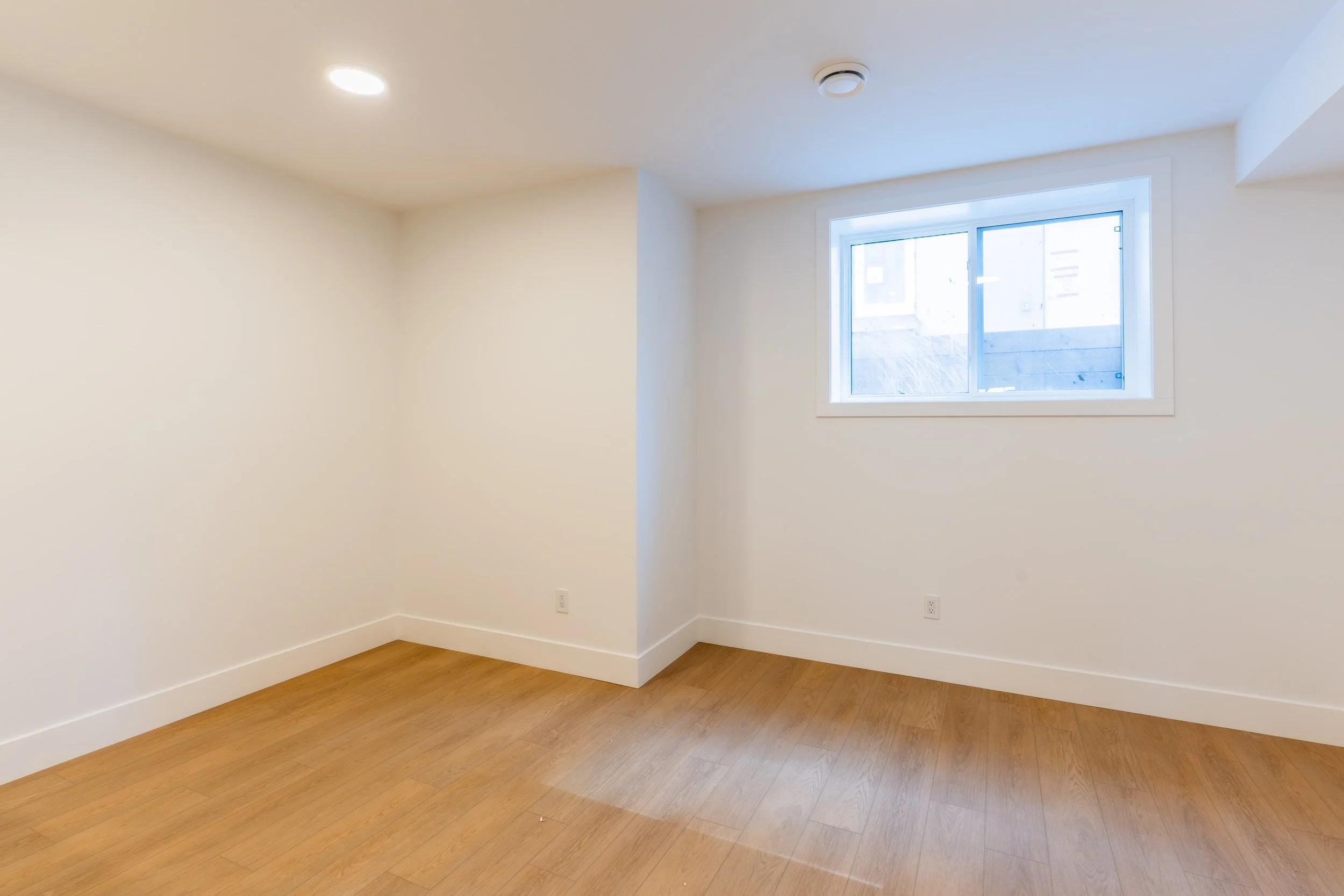 Bright open room with hardwood floors and window in Unit 203R Uptown 17th Calgary 1-bedroom lower suite rental near 17th Ave SW by Suite Getaways