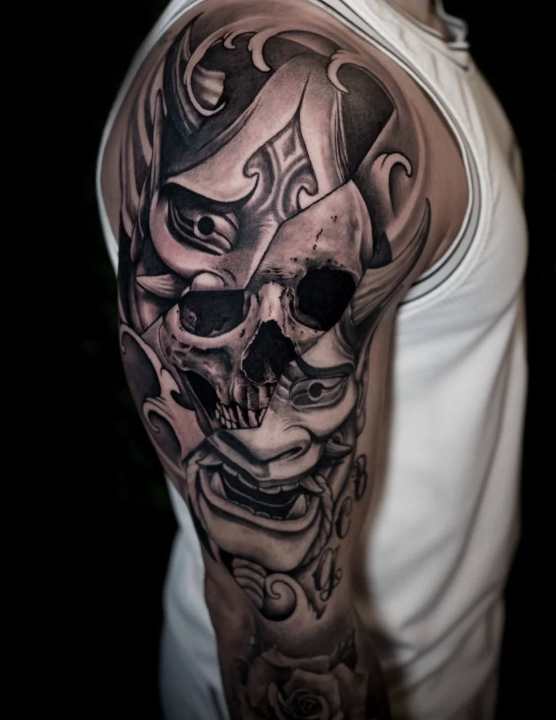 Black and gray tattoo sleeve featuring a skull, a clown face, and decorative elements.