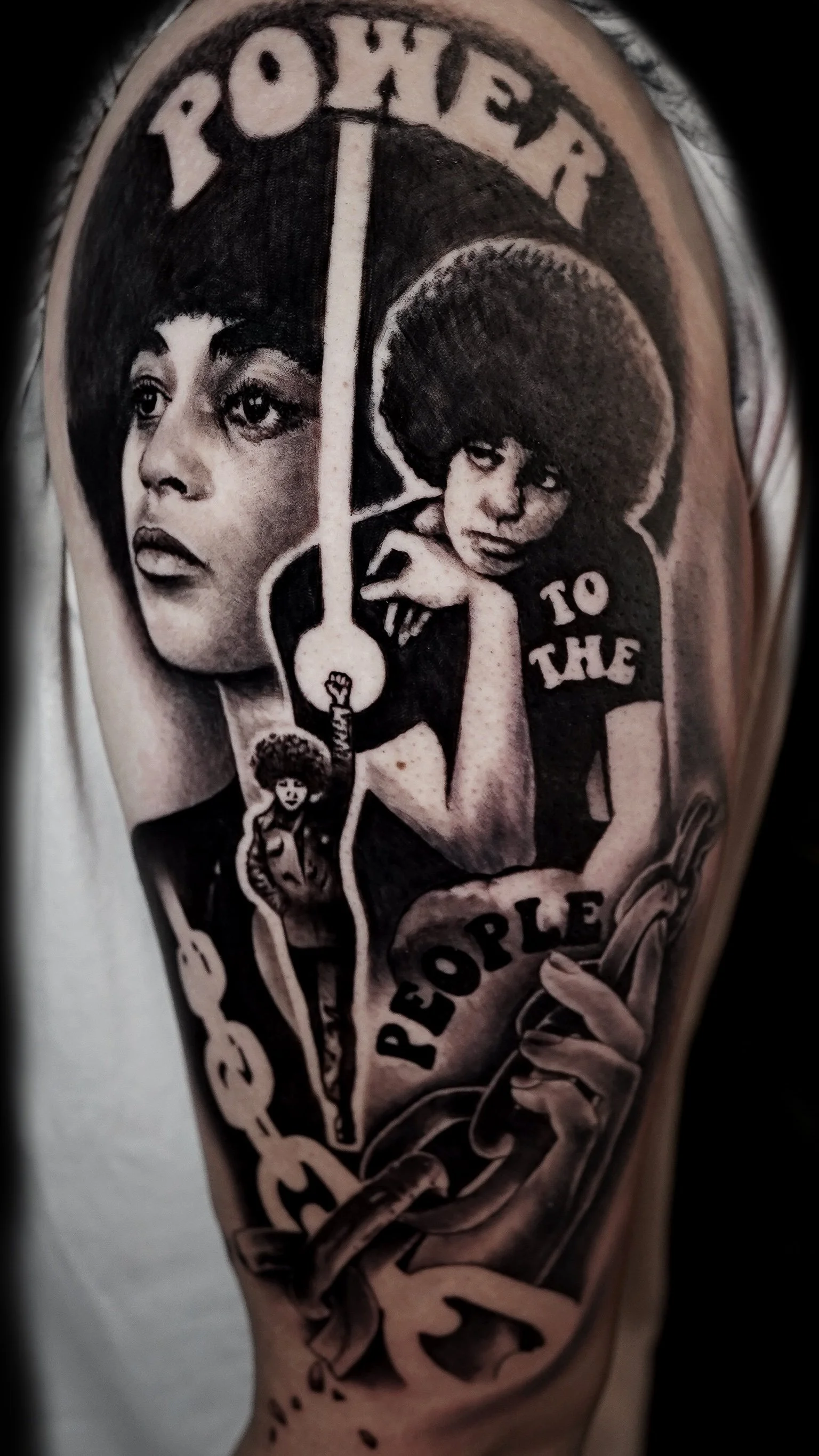Black and gray tattoo on a person's arm depicting cultural and political images, including a woman with short hair, musical notes, and text that reads 'RESPECT THE PORLE'.