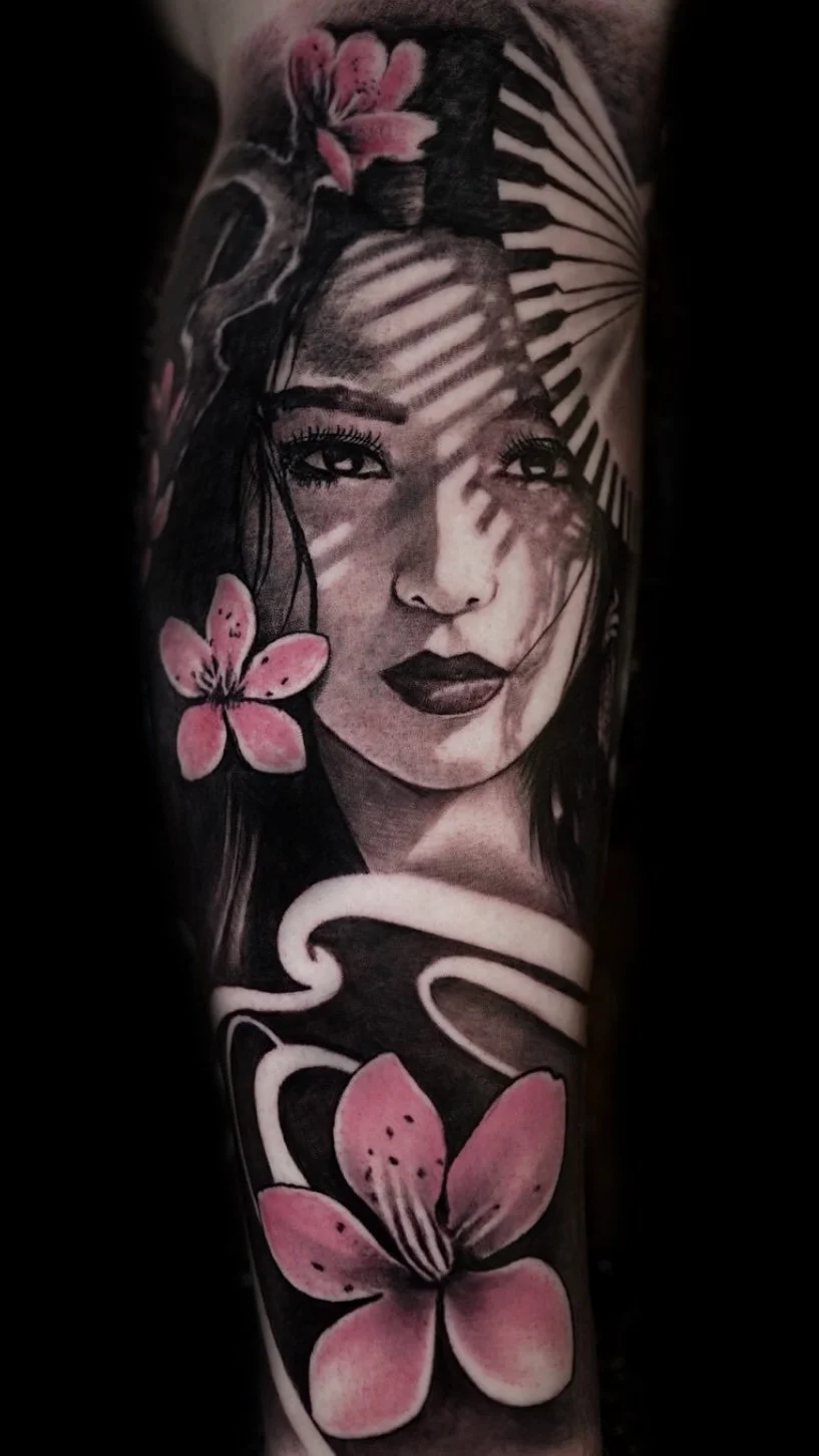 Tattoo of a woman’s face with pink flowers and decorative black and white elements.