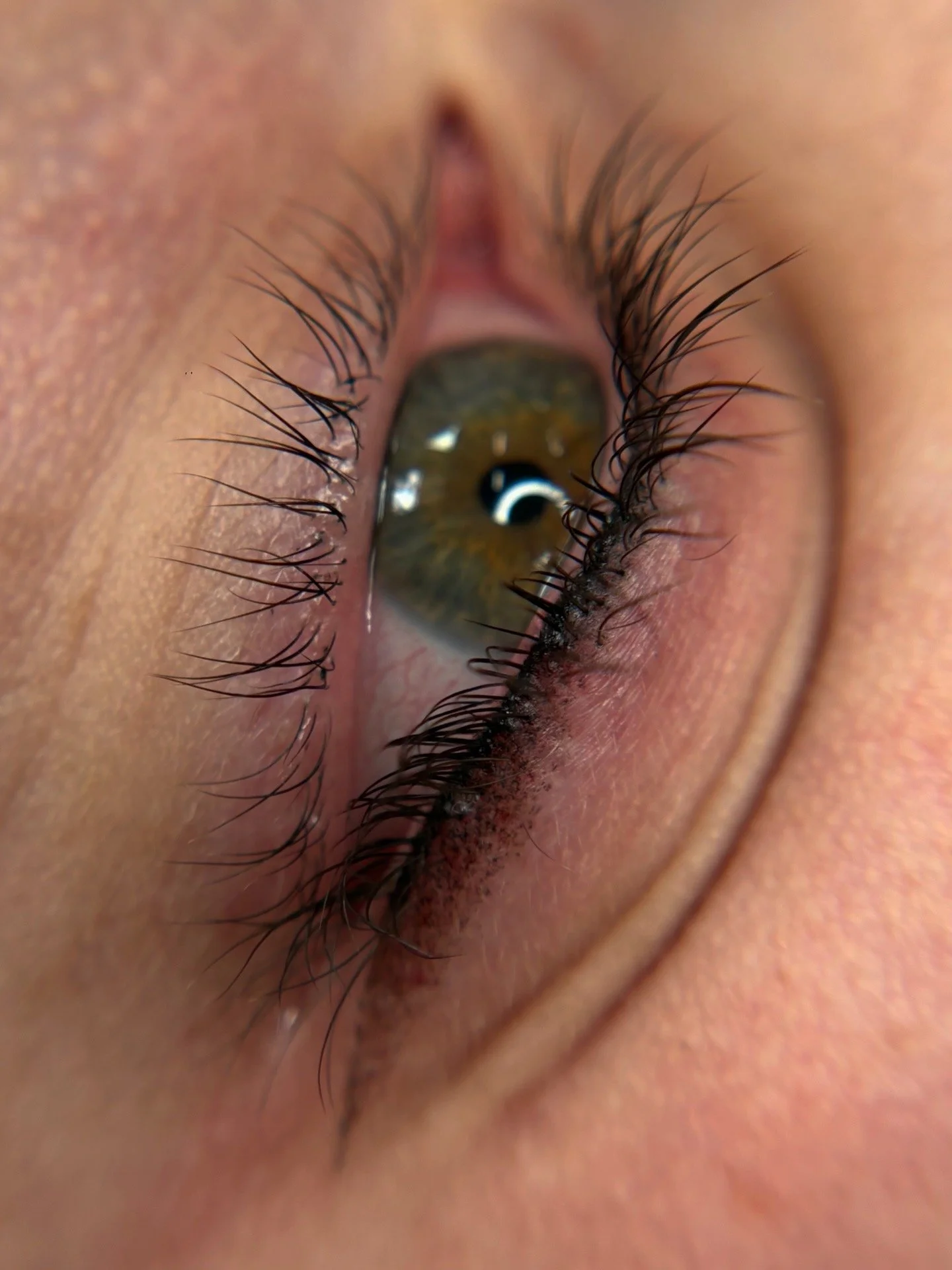 Close-up of a human eye with long eyelashes and brown iris.