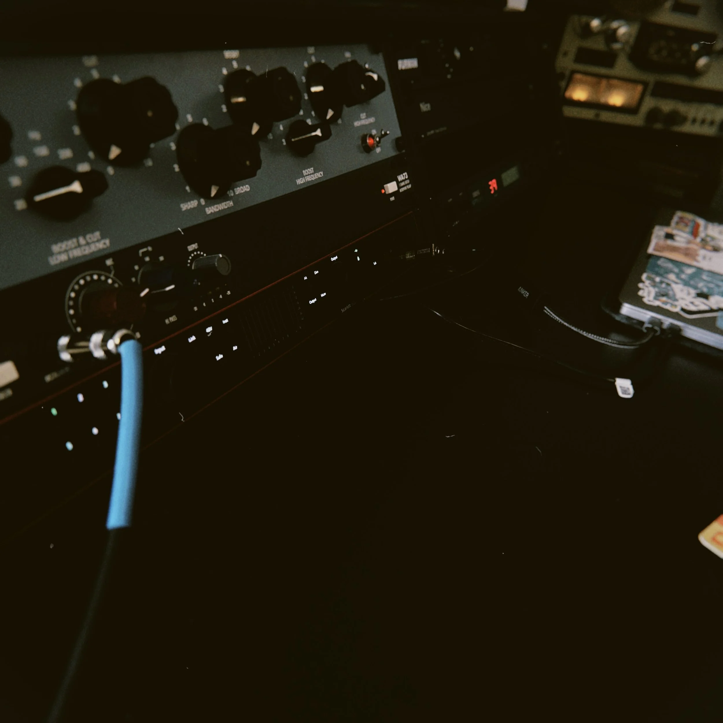 Close-up of audio equipment controls, including knobs and switches, with a blue cable plugged into the equipment.
