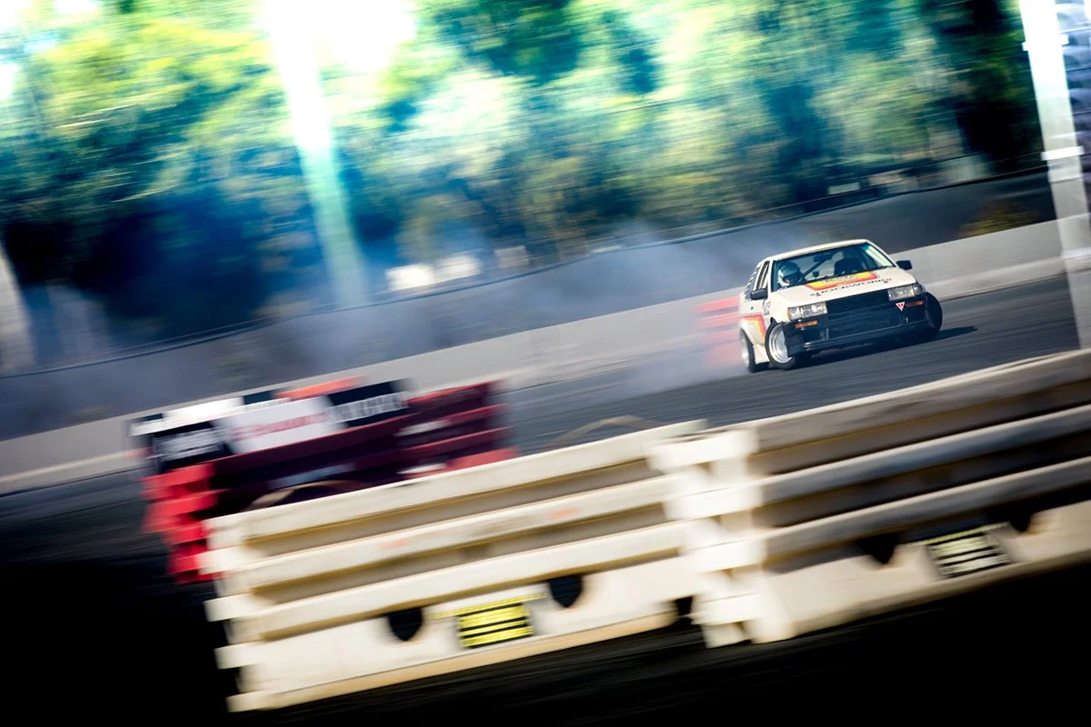 Drift car approaching a corner behind a racetrack barrier