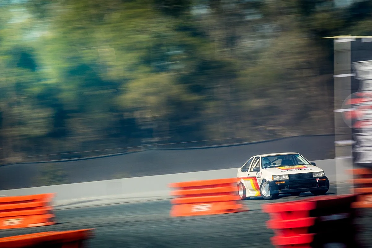 Drift car passing red barriers during a track session