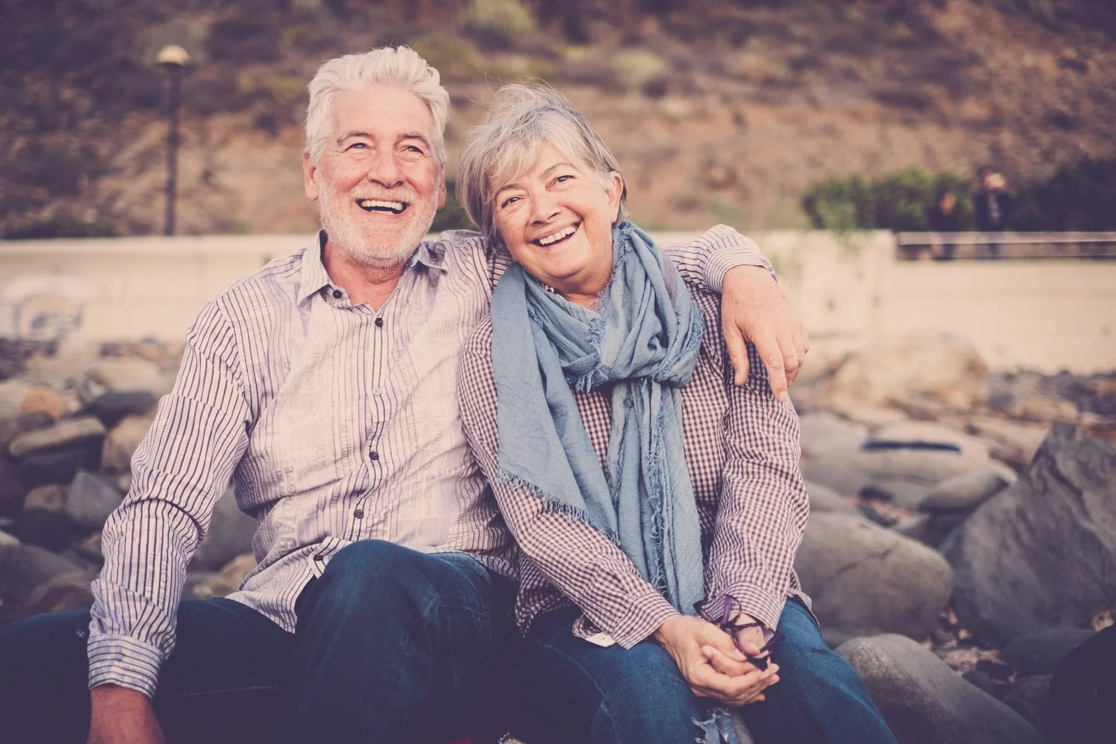 Smiling senior couple sitting by the coast in Huntington Beach, California
