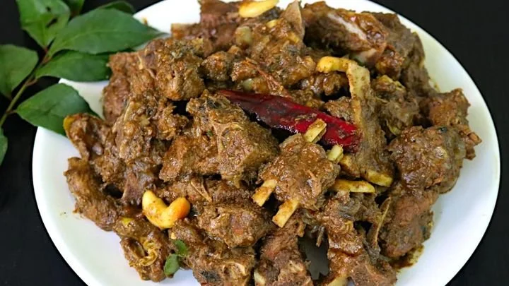 A plate of spicy beef curry with tendons, garnished with a dried red chili and a sprig of fresh green herbs.