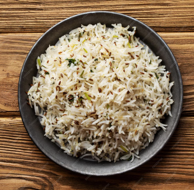 A black bowl filled with cooked white rice mixed with herbs and seeds, placed on a wooden surface.